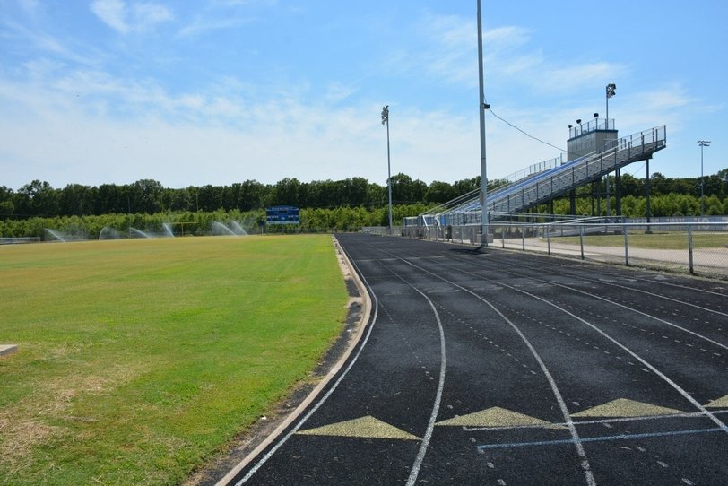 Outdoor running track with visible surface wear and cracks along lane edges, showing early running track cracks and surface issues.