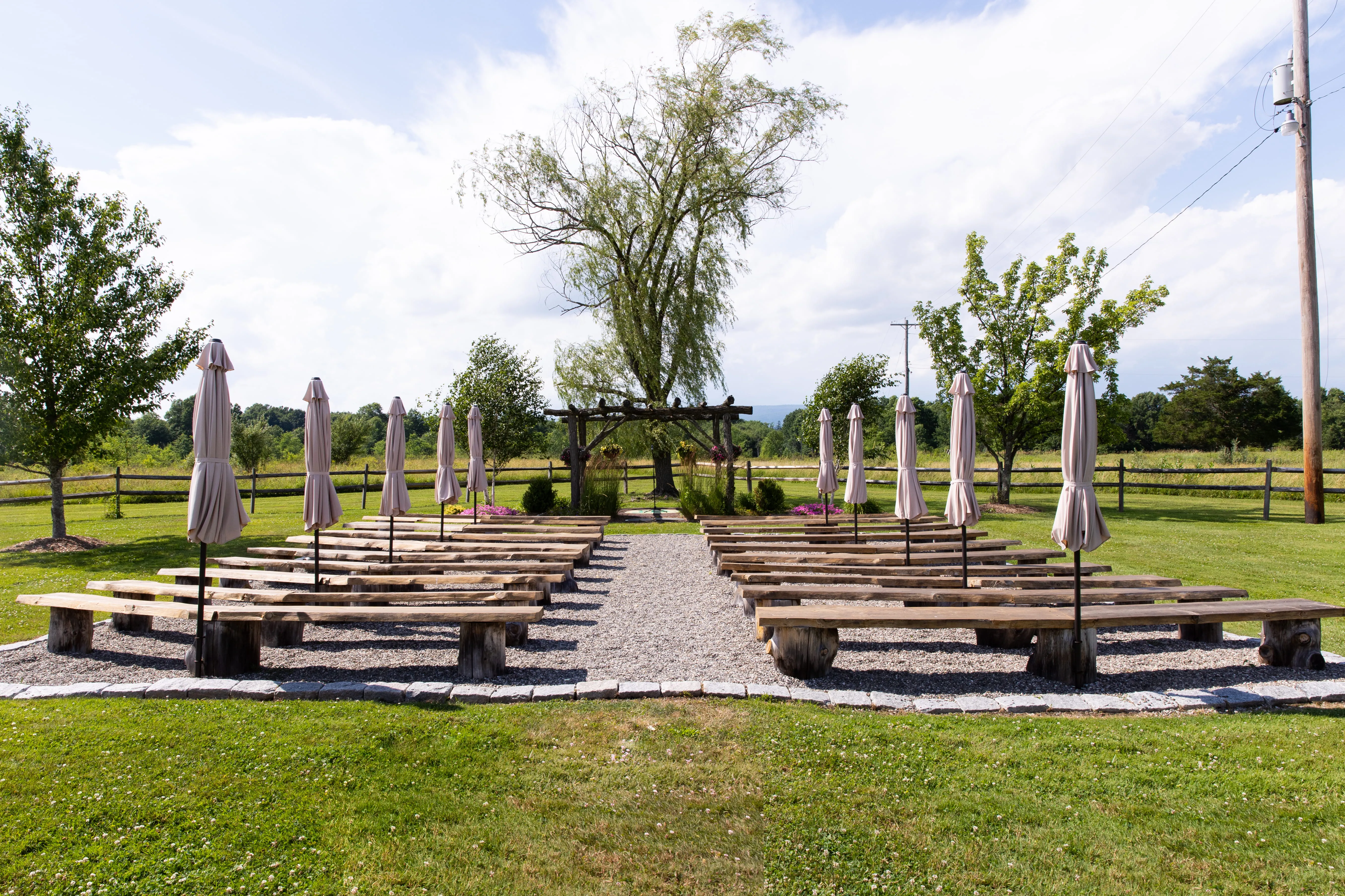 Outdoor wedding ceremony setup with wooden arbor and scenic landscape