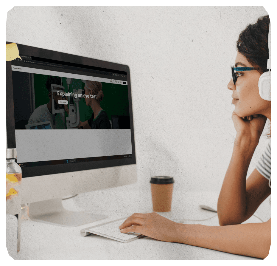 Female with headphones on a desk doing a bespoke e learning on her computer