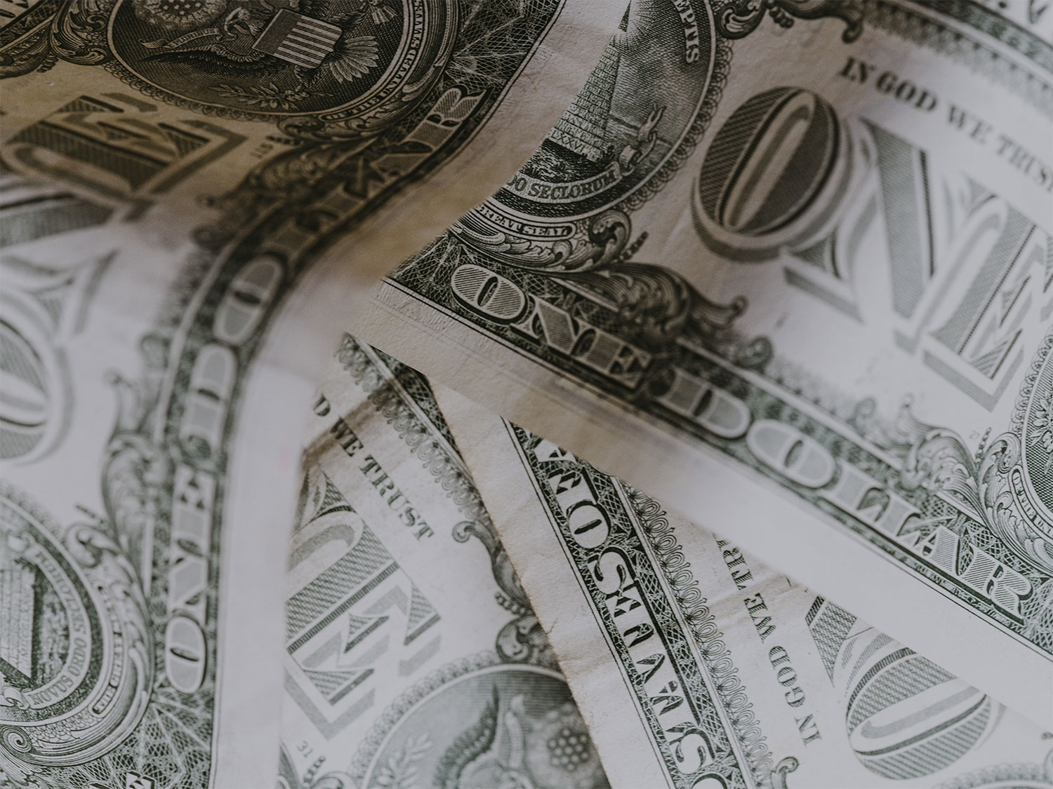 Close-up of crumpled US dollar bills arranged in a disorganized manner.