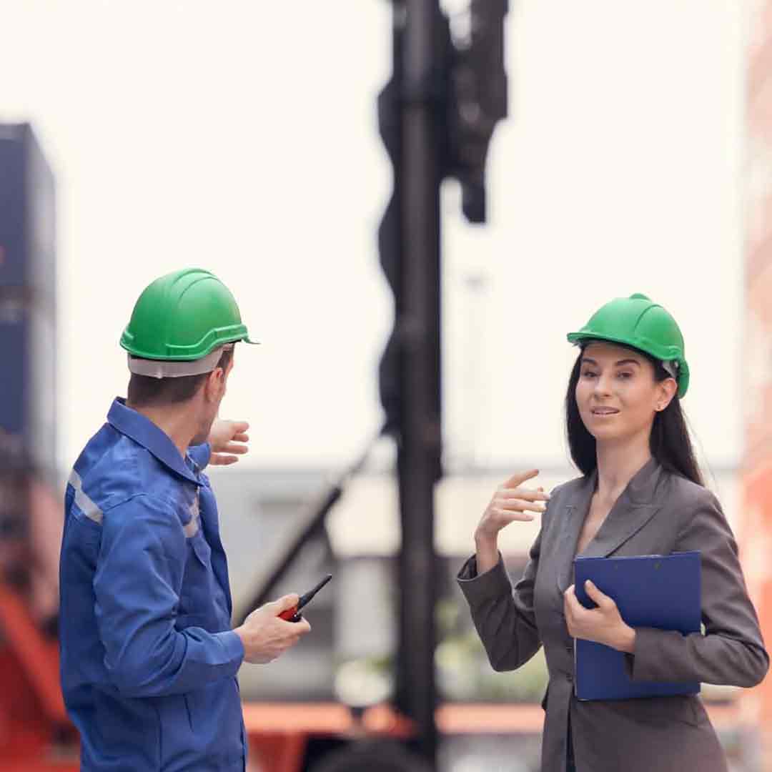 Інженер і менеджер у захисних касках планують міжнародне перевезення вантажів