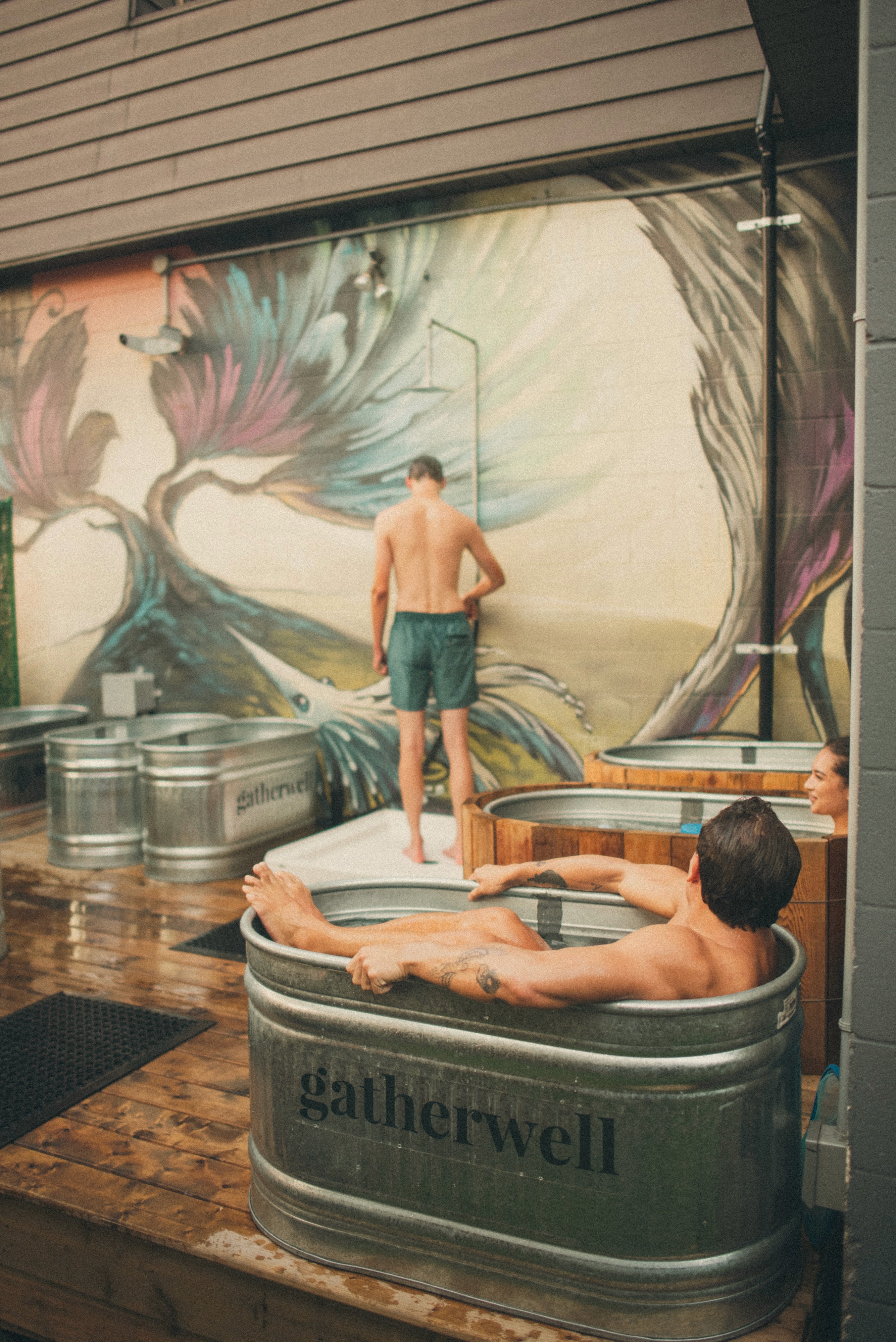 Close-up of a man stretching in a light gray athletic top with a red "pyra." logo on the sleeve.