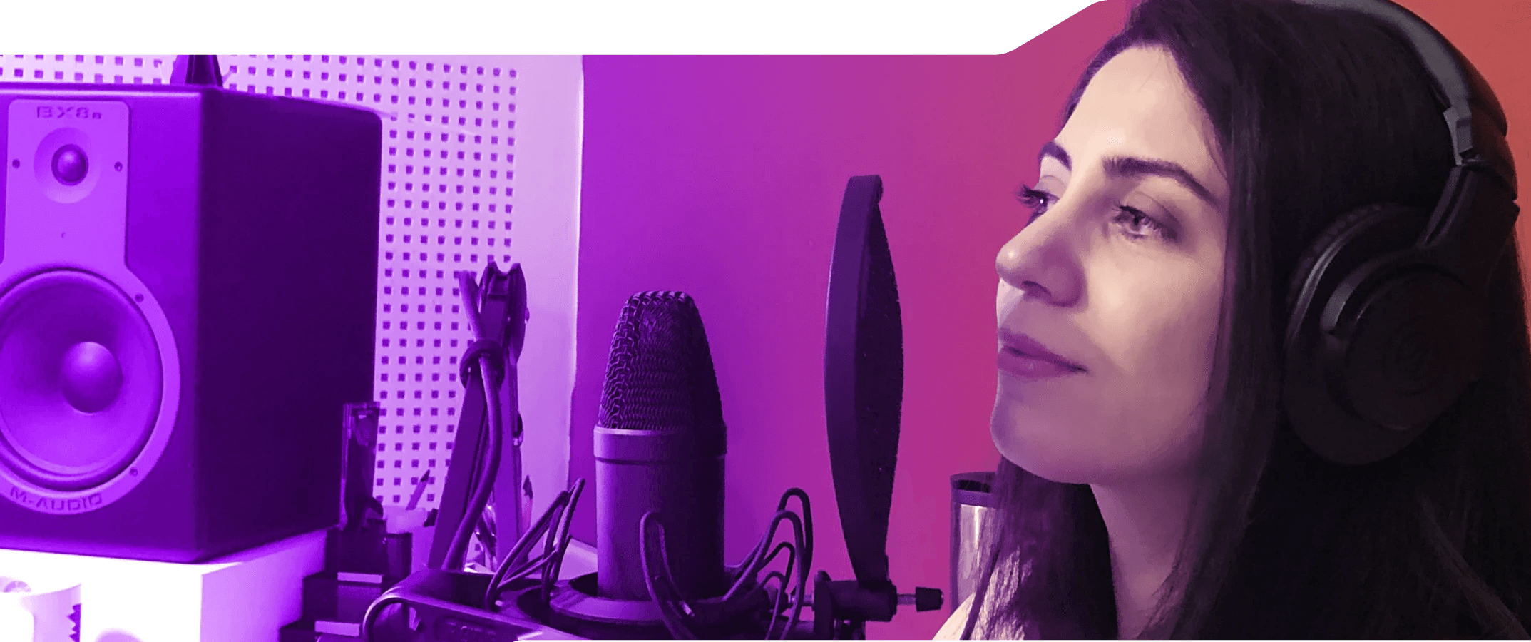 Fotoğrafta, stüdyoda kulaklık takmış ve mikrofonun önünde duran bir kadın, Öykü, görülüyor. Arka planda bir hoparlör var.