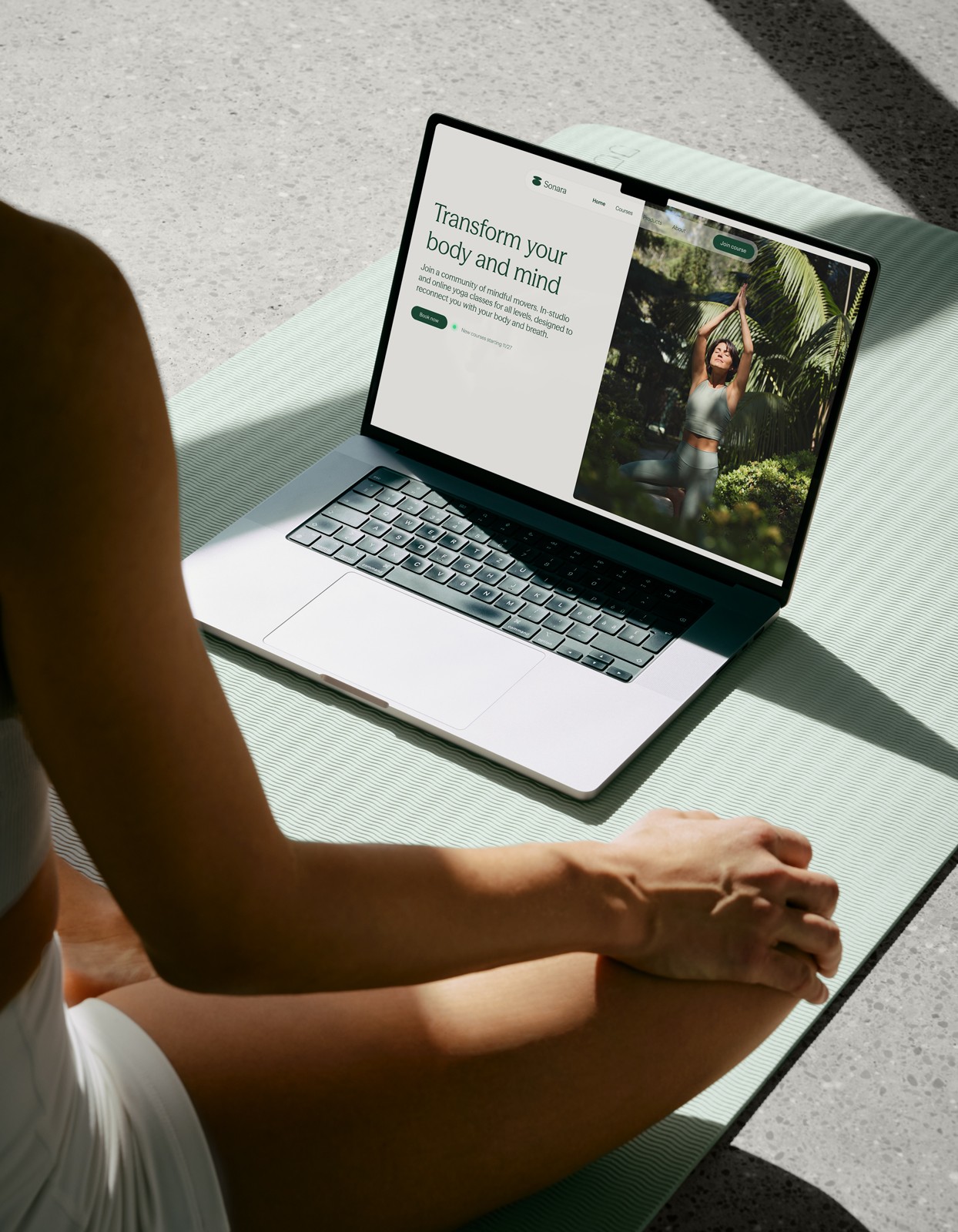 Woman in lotus pose with laptop and yoga mat