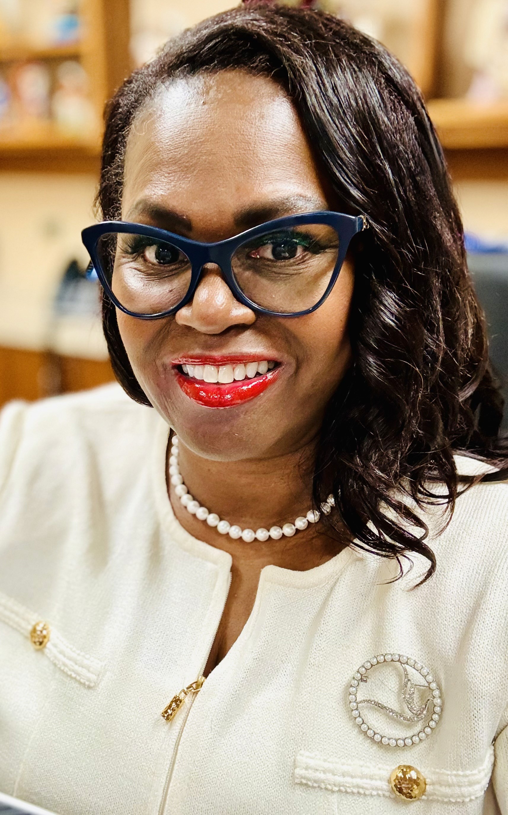 A person with long hair stands against a bright, hazy background, reaching out with one hand.