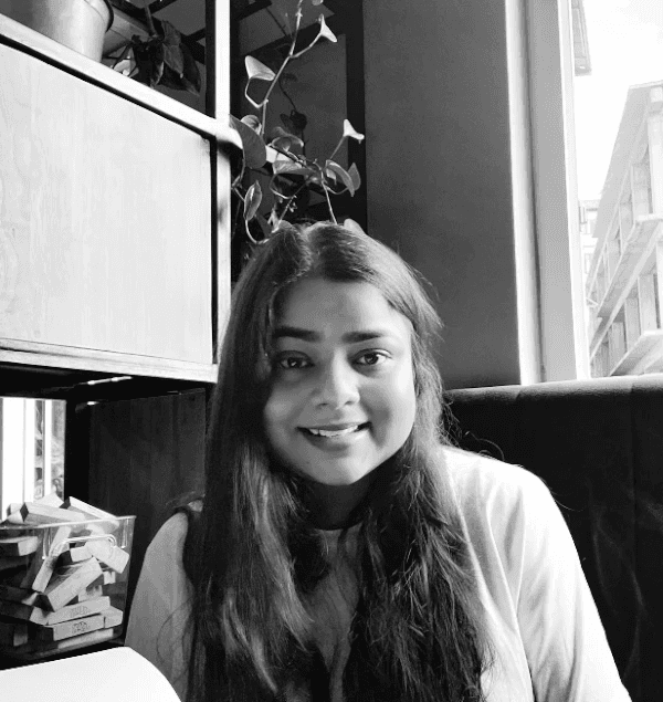 Woman working on a laptop computer at a table in a bright room.