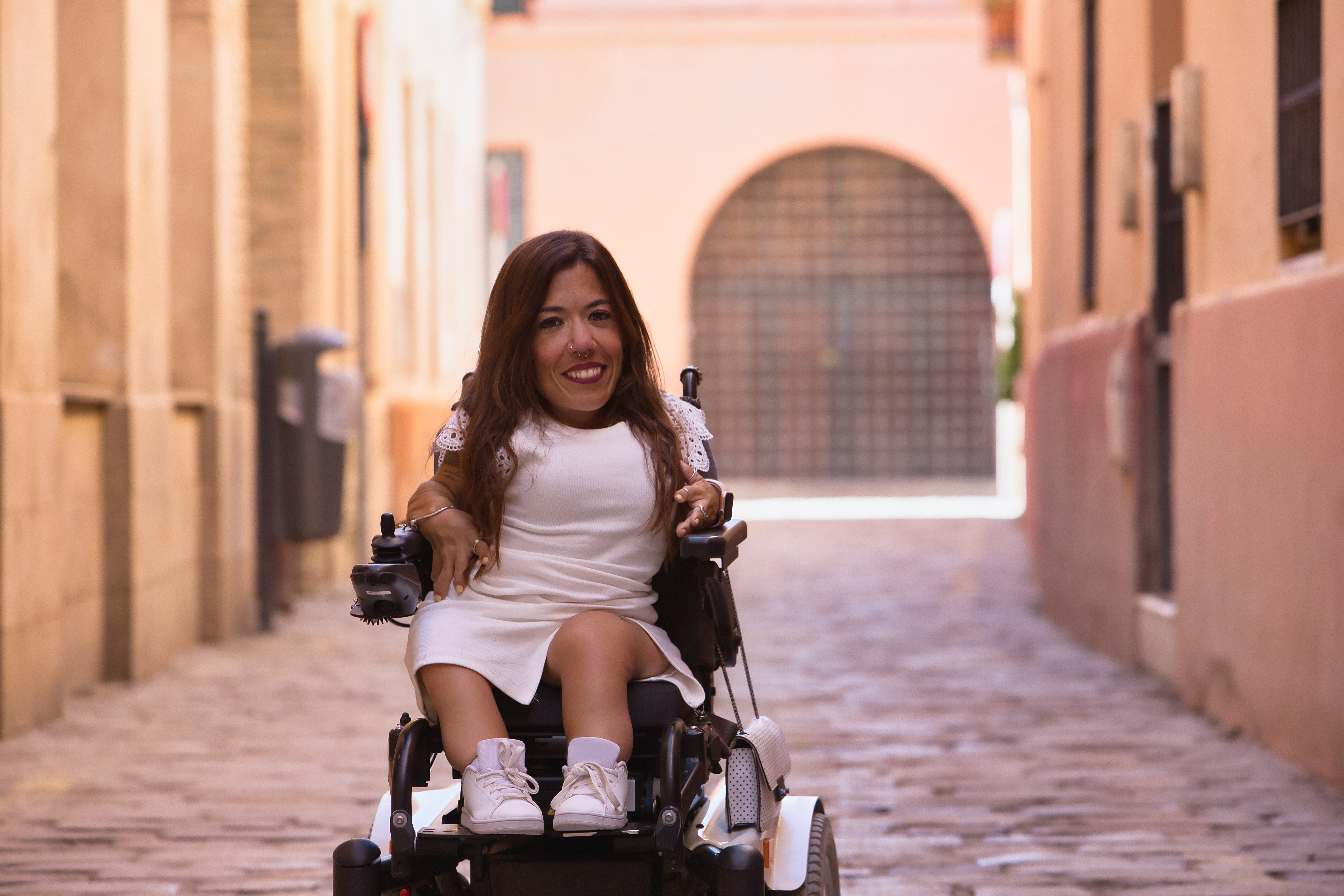 This image is of a young and beautiful girl in a wheelchair. She is smiling at the camera.