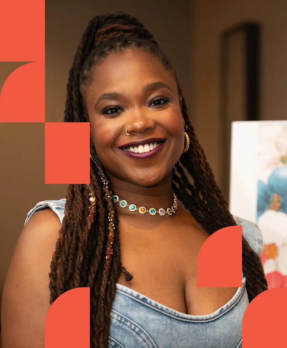 Smiling woman with braided hair and a colorful necklace, wearing a denim top. There's a warm, inviting atmosphere with geometric orange overlays.