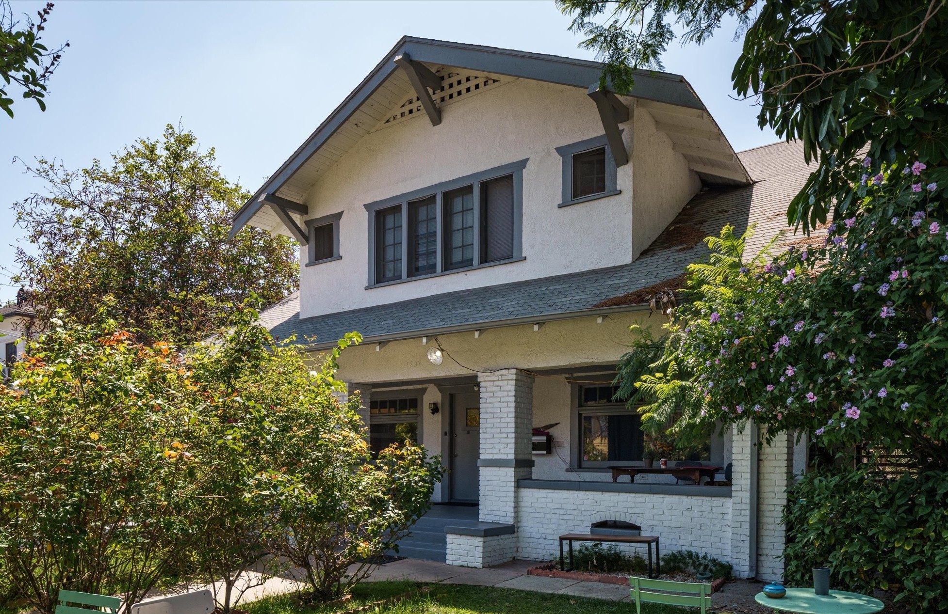 A charming two-story house at 1807 n van ness, surrounded by greenery, featuring a large front porch and windows.