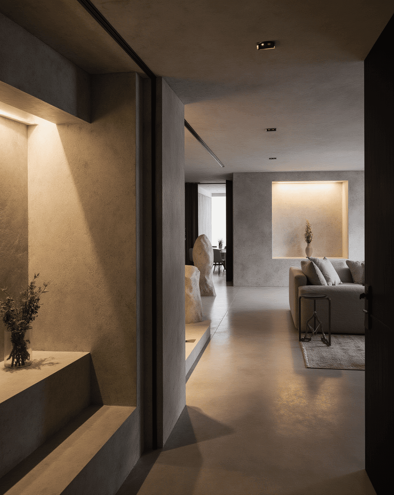 Minimalist living space with textured walls, built-in lighting, and neutral furniture in a soft modern interior.