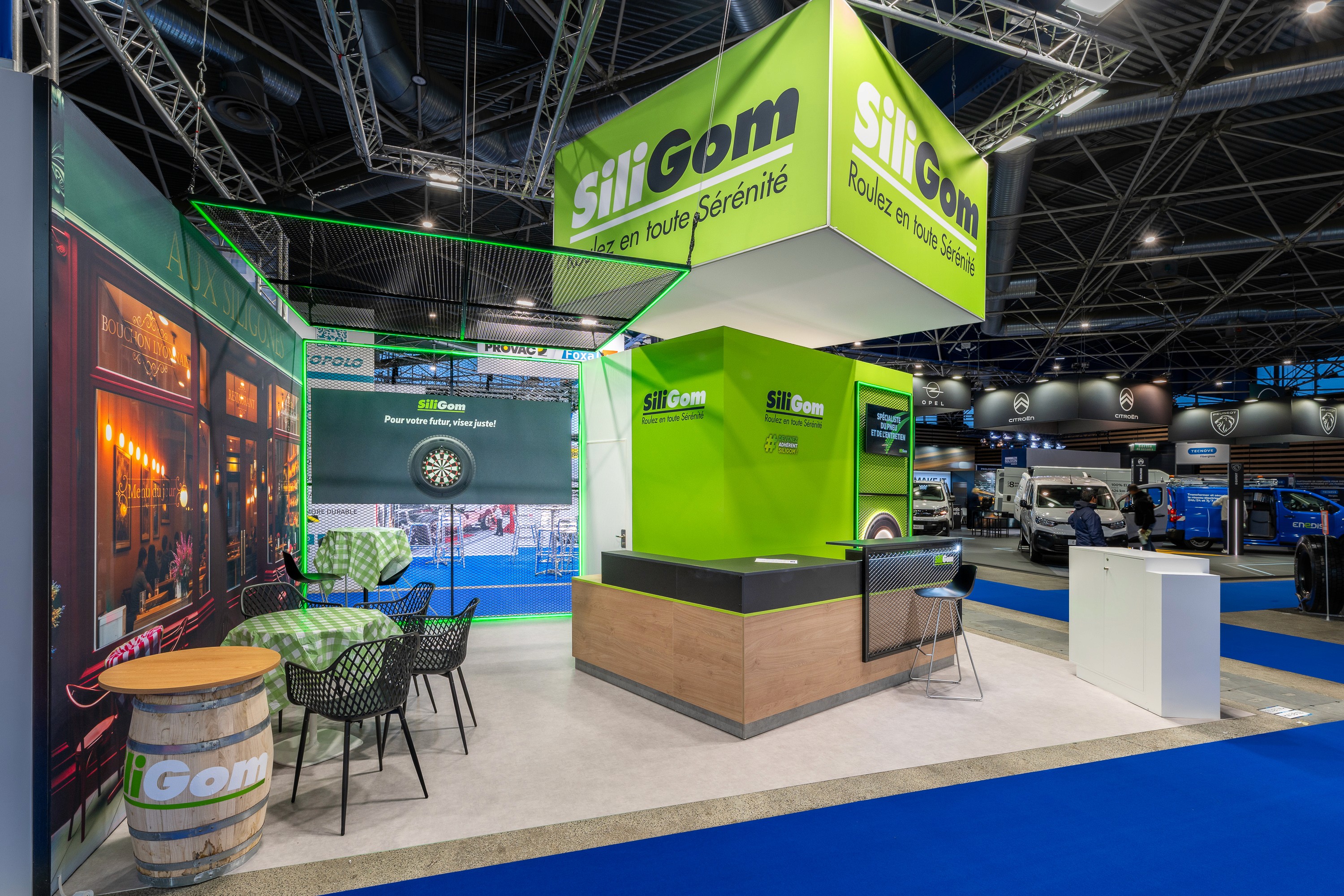 Stand SiliGom Solutrans Lyon 2026 conçu par Expace – vue d'ensemble du stand vert avec mobilier bois clair, zone d'accueil visiteurs et identité visuelle pneumatique poids lourd