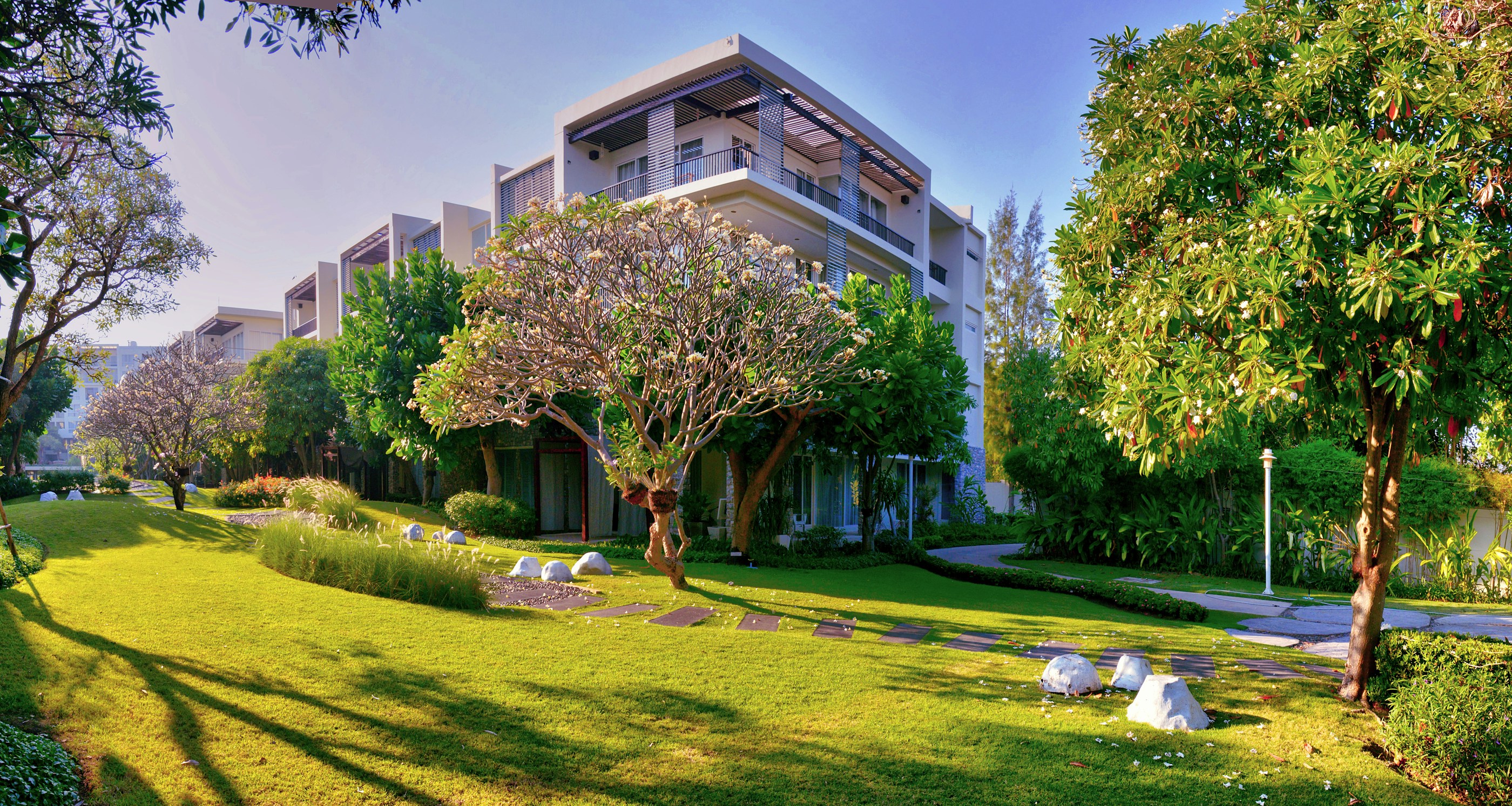 Residential buildings arranged around a shared lawn, planting and pedestrian paths; illustrative photography