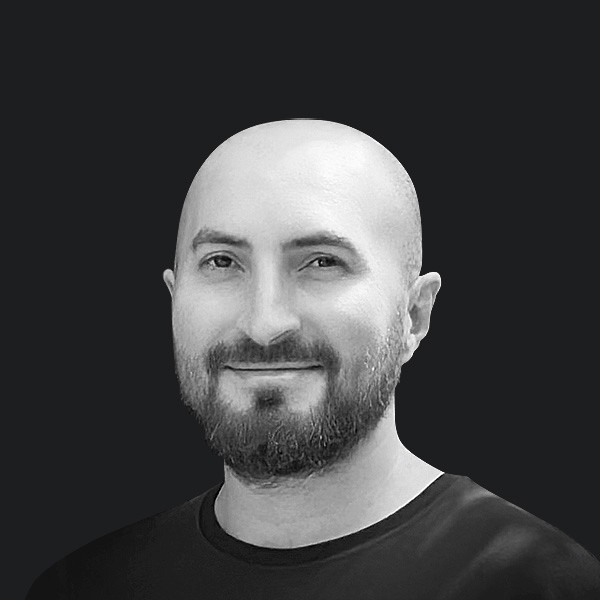 Woman working on a laptop computer at a table in a bright room.