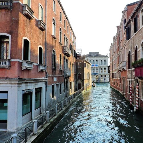 一条狭窄的运河两侧矗立着历史悠久的建筑，平静的水面倒映着这些建筑。