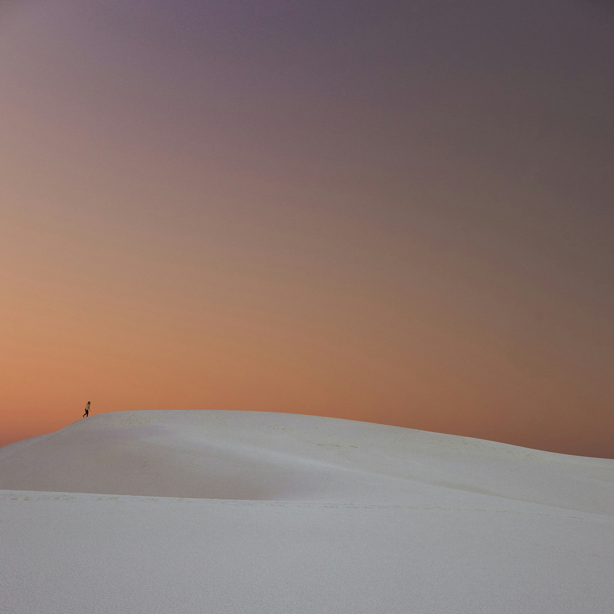 Wide angle of a person walking over sand dune