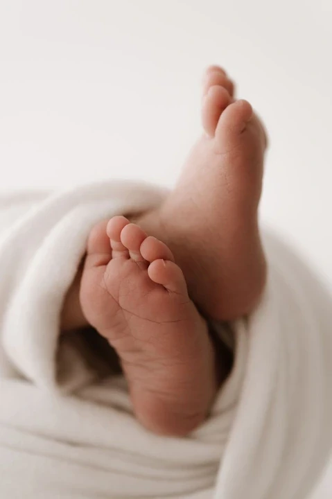 Baby feet emerging from a white blanket