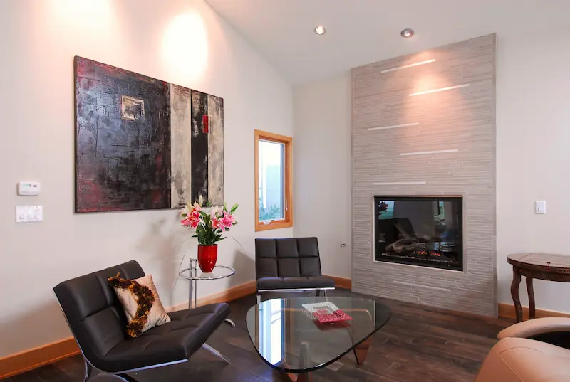 Modern living room with sleek fireplace, contemporary art, and glass coffee table in Irvine Transitional Modern. Photo by Chris Darnall.