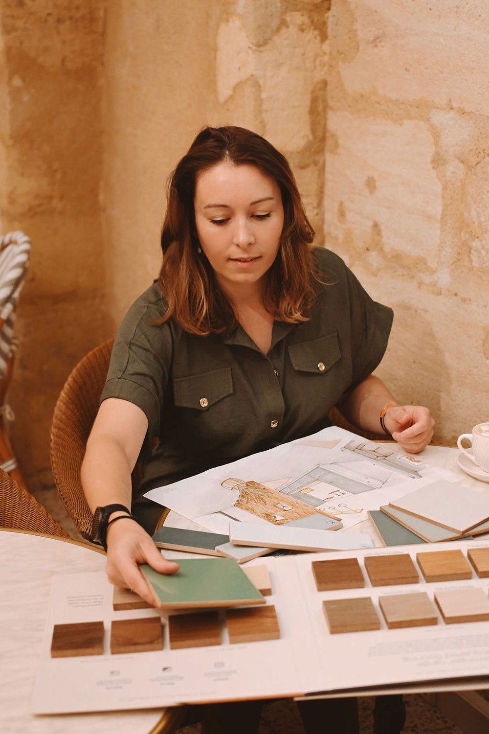 Eva Hostein, architecte d'intérieur spécialisée ERP à Bordeaux, sélectionnant des échantillons de matériaux pour un projet de local professionnel en Gironde