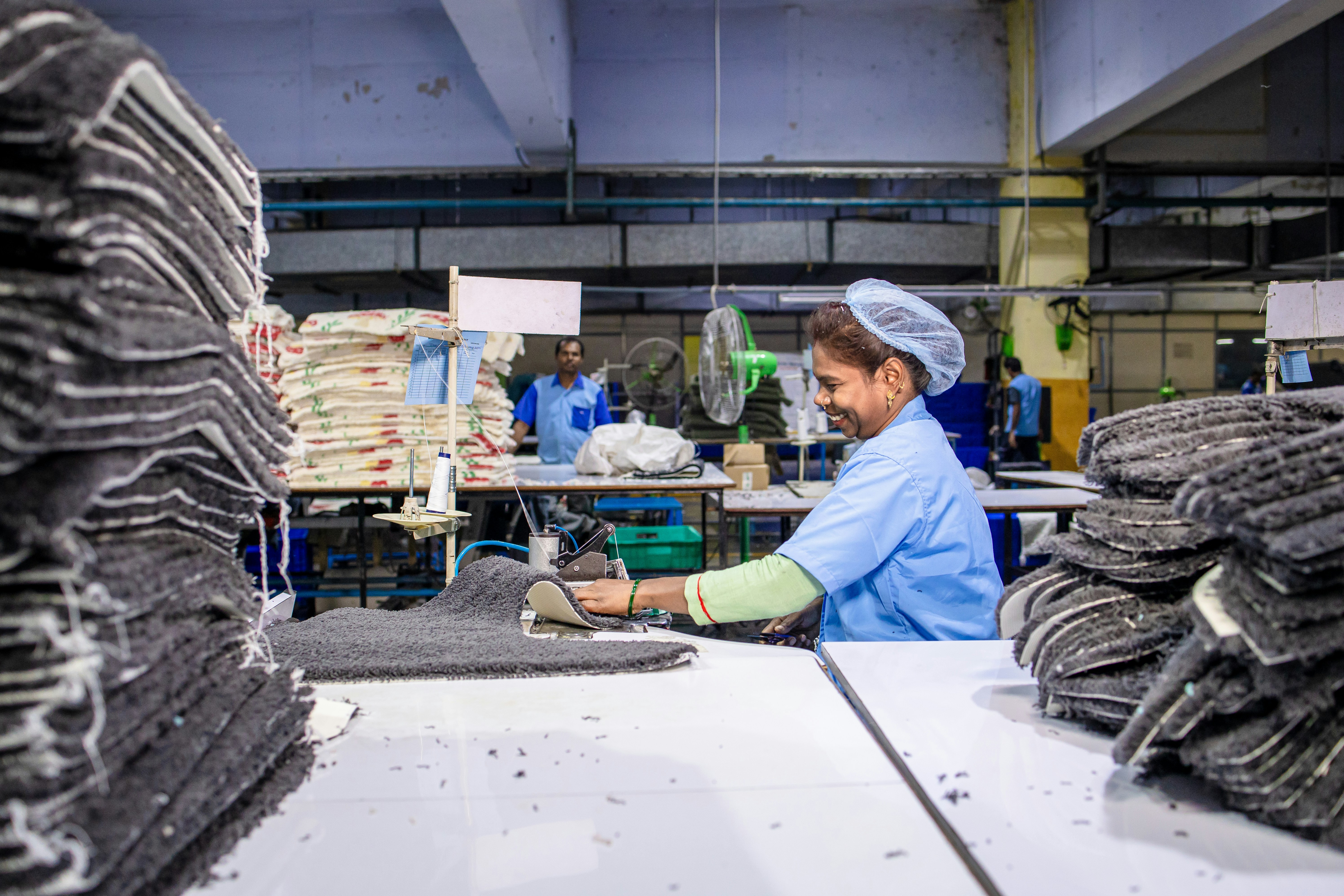 A woman works at a factory, amidst supplies.