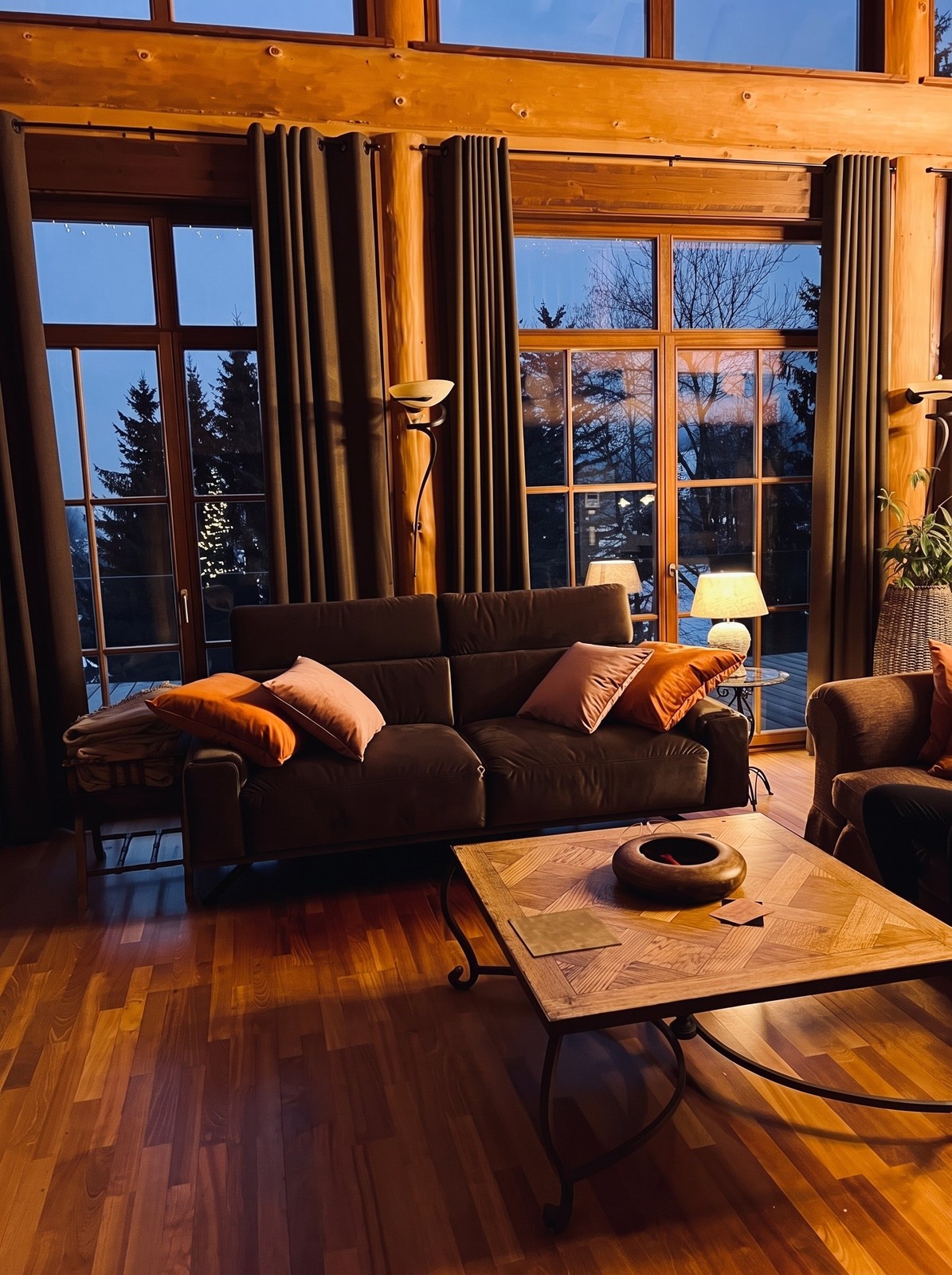 The lounge at dusk, sofas facing tall windows