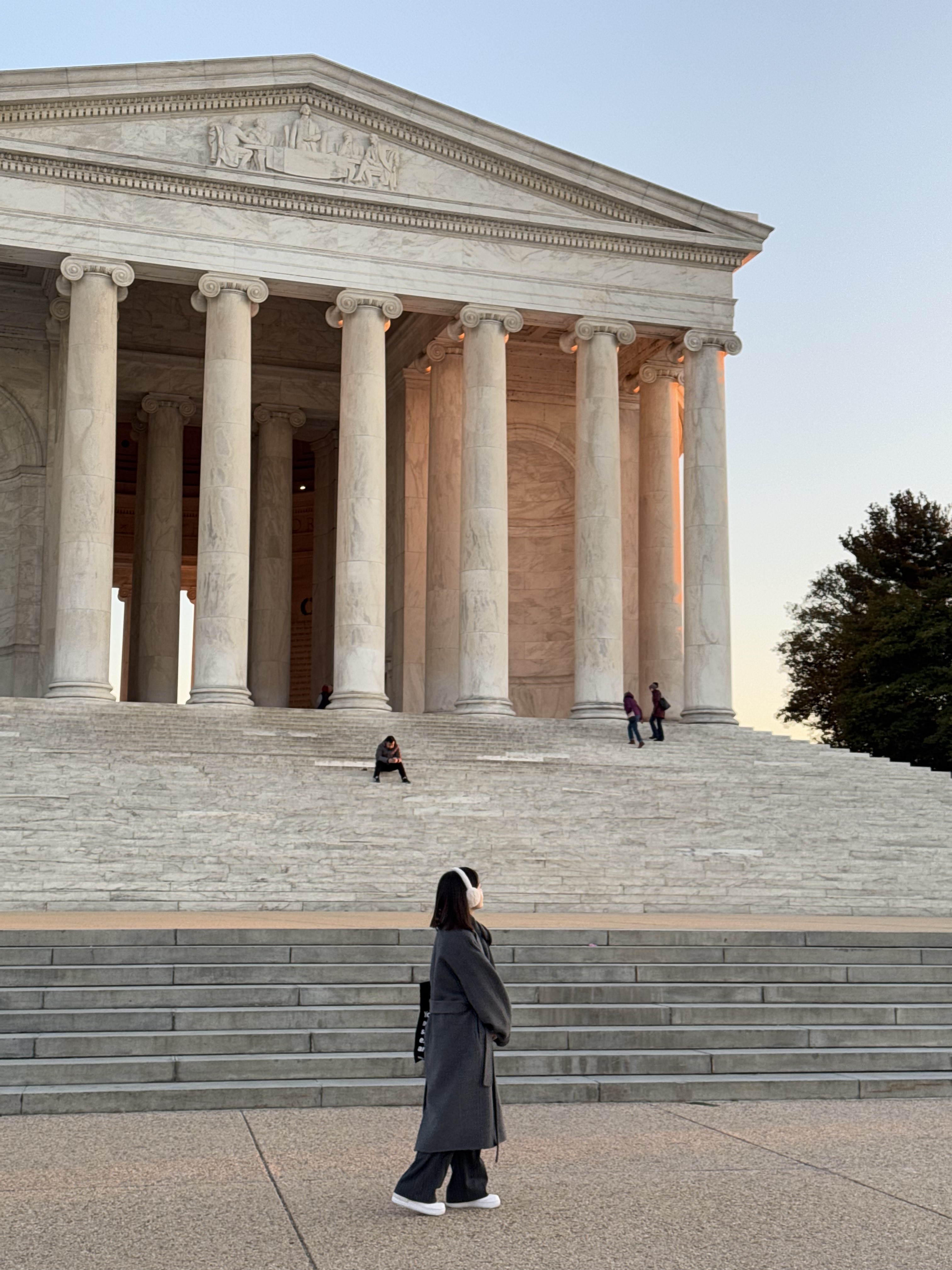 Cinematic street photo of a person riding a bicycle past a large windowed building during golden hour.