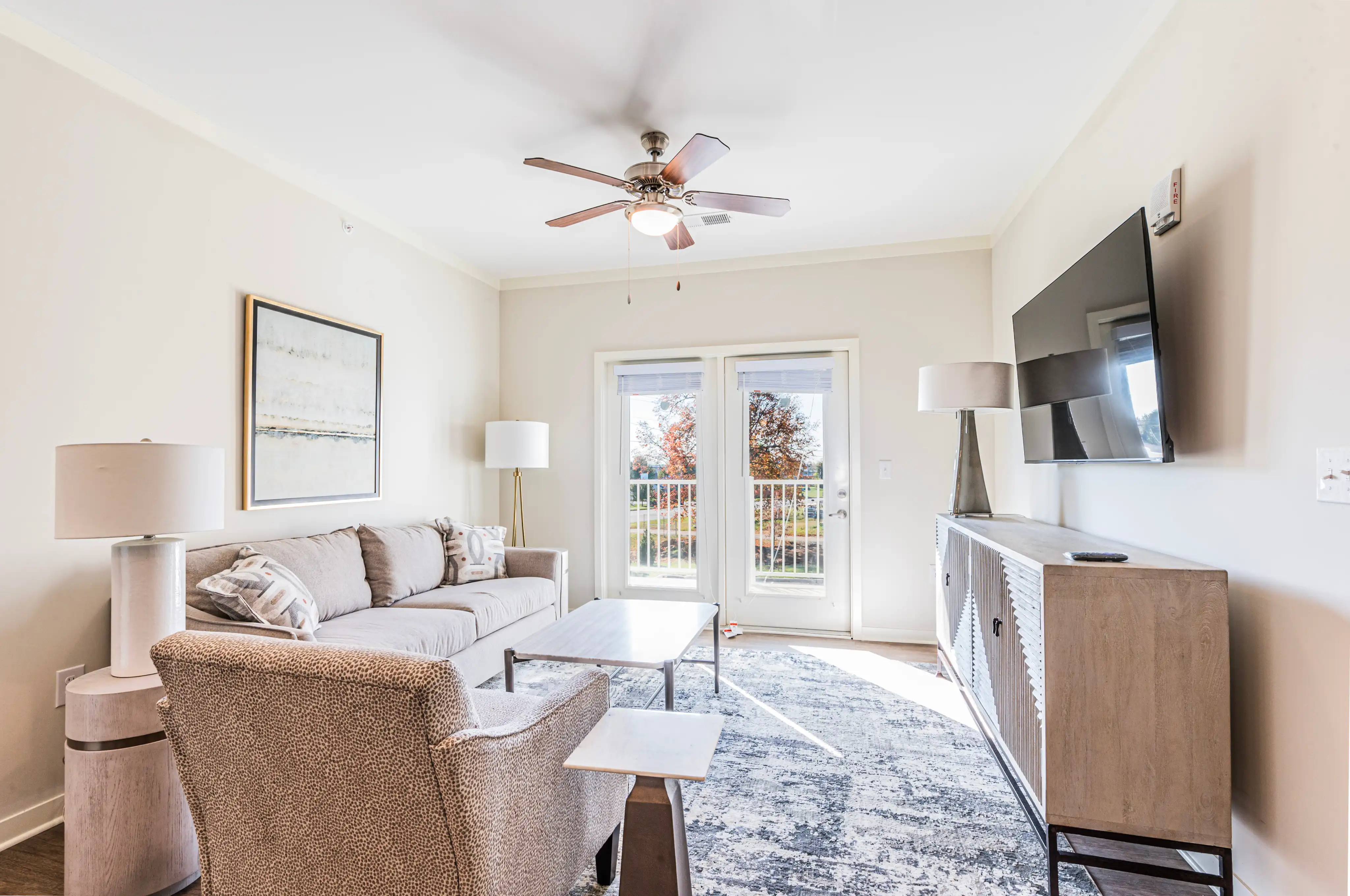 Furnished apartment living room with a sofa, ceiling fan, and balcony doors at The Reserve at Cool Springs, Elizabethtown, KY