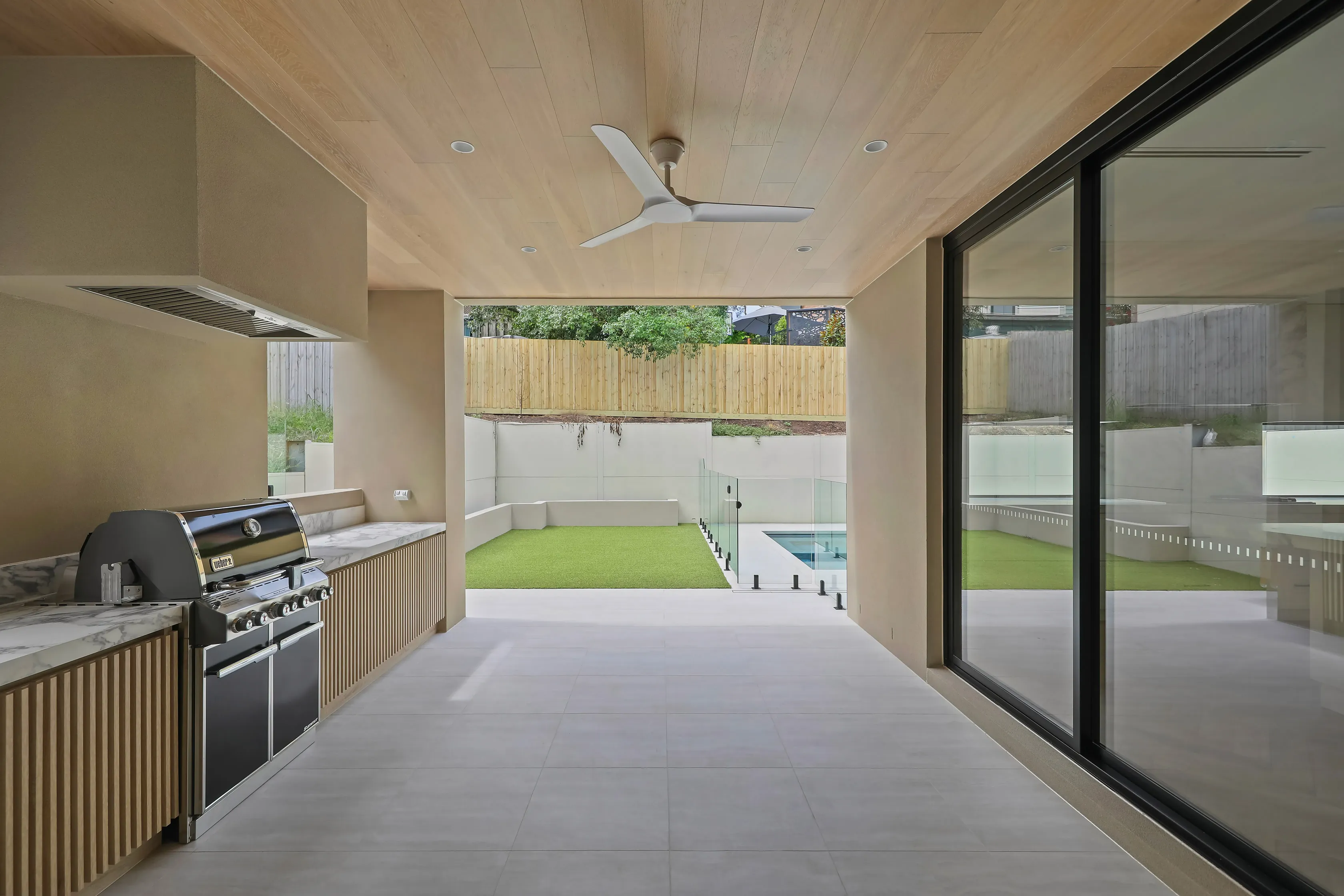 Templestowe covered alfresco with a timber-lined ceiling, stainless barbecue and marble bench overlooking the pool and lawn