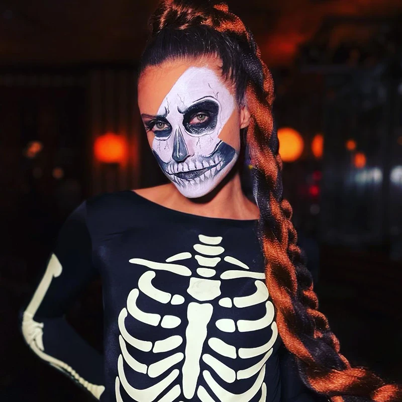Performer with half-face skeleton makeup and skeleton costume