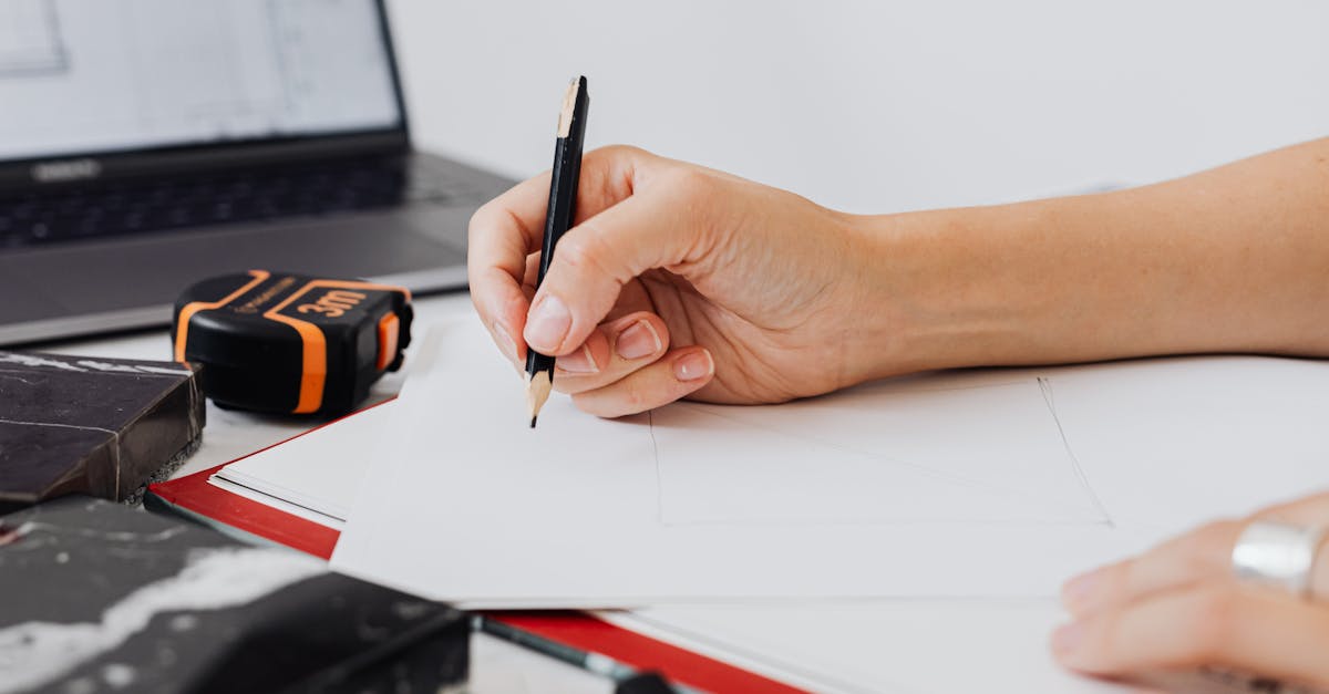 Close-up of a designer's hand sketching with a pencil on paper, illustrating architectural planning.