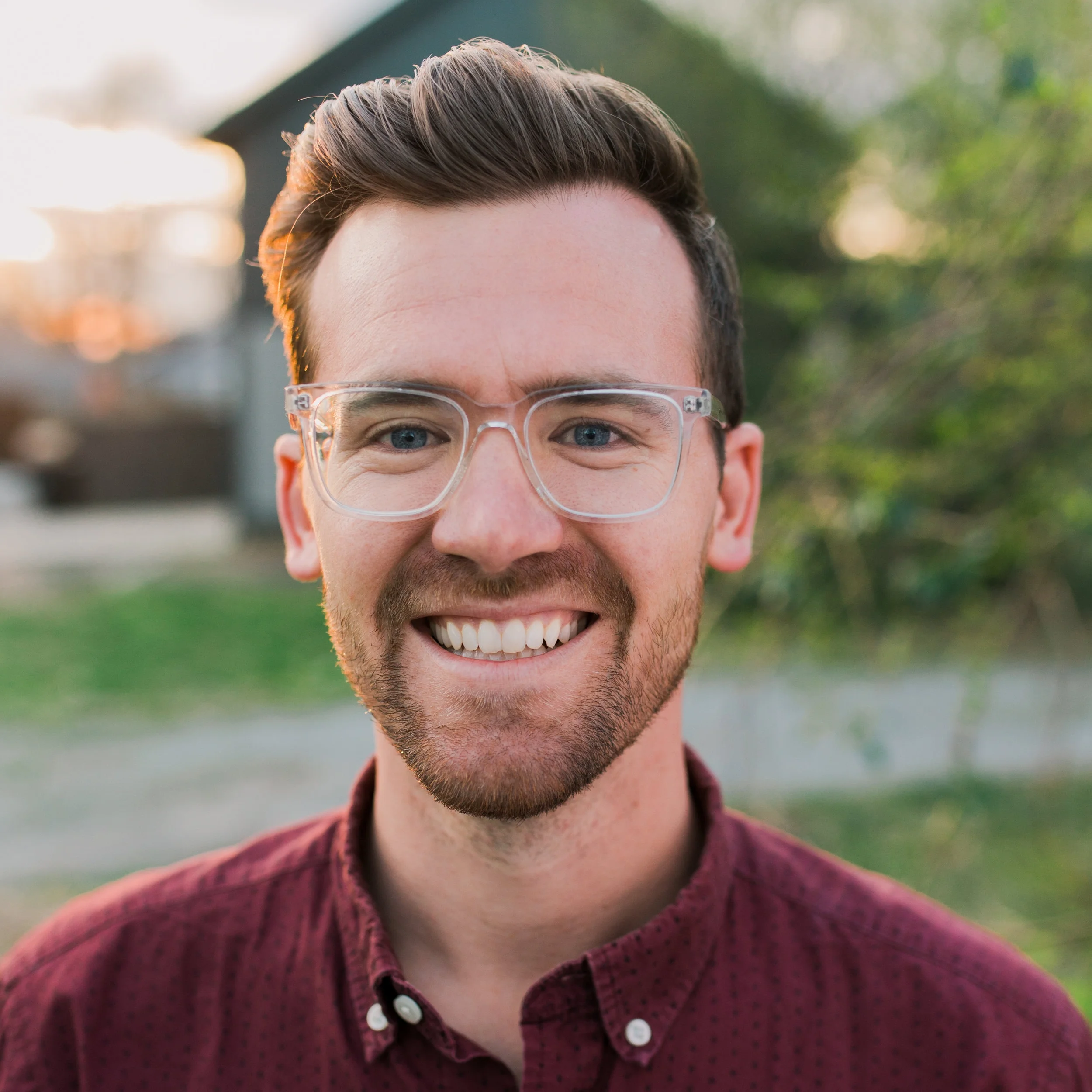 A close-up of a person wearing green-tinted glasses, with a serious expression and smooth skin.