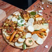 A rustic table set with various traditional pastries and a small bottle, surrounded by green foliage.