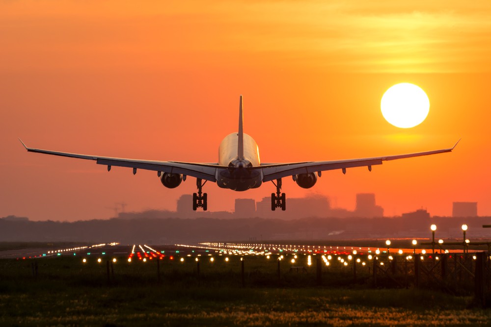 Airplane flying over mountains at sunset