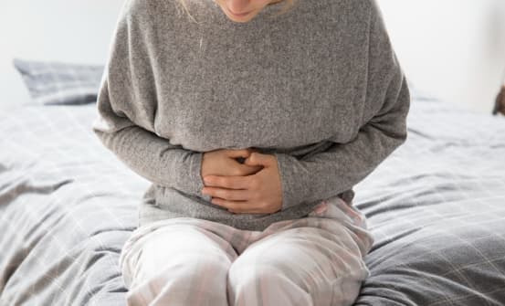 Жінка тримає себе руками за живіт