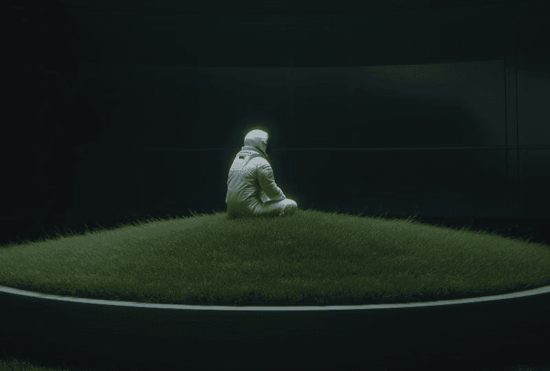 A solitary person in a white suit sitting in a dark, expansive void, illuminated by a single, soft overhead light source.