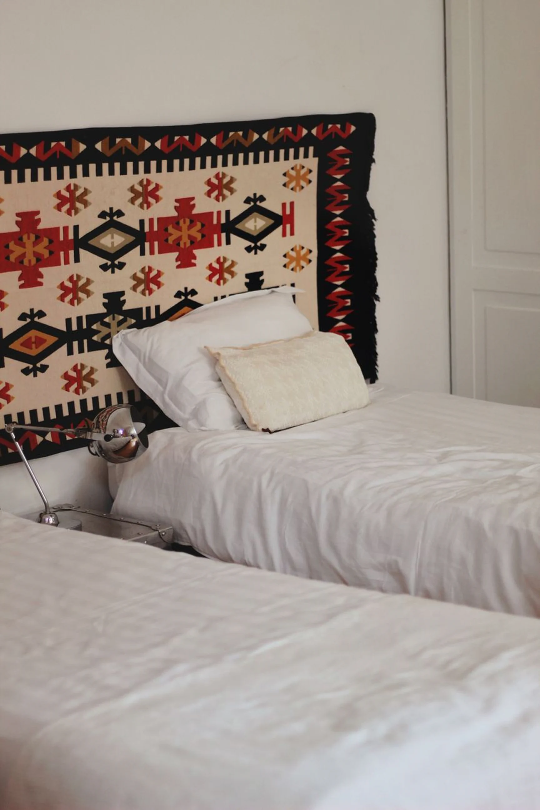 Close-up of the garden twin room beds with white bedding and a patterned wall accent.