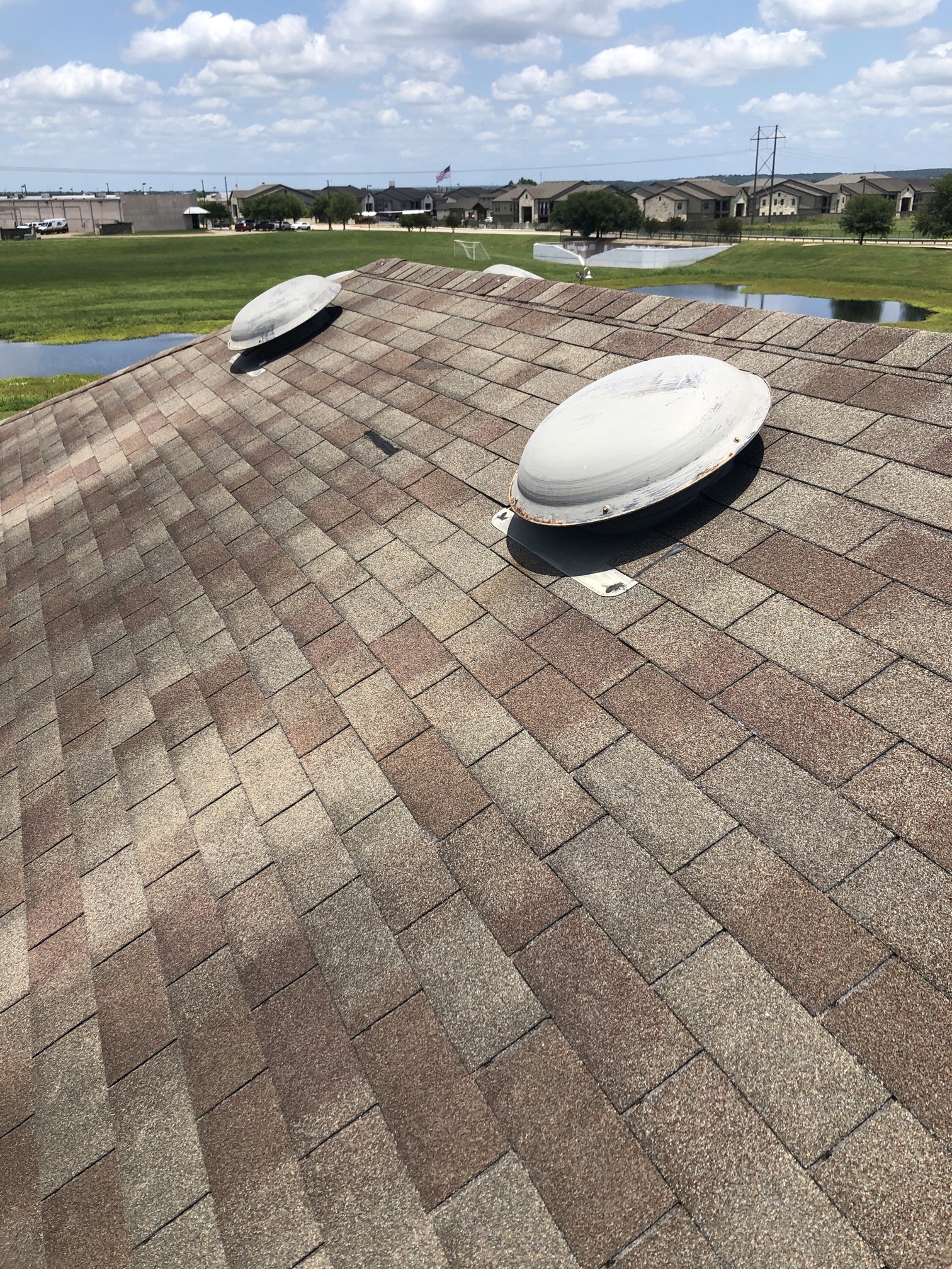 Two round roof vents on a shingle roof. Intake and exhaust sizing must use the exact vent model’s published rating.