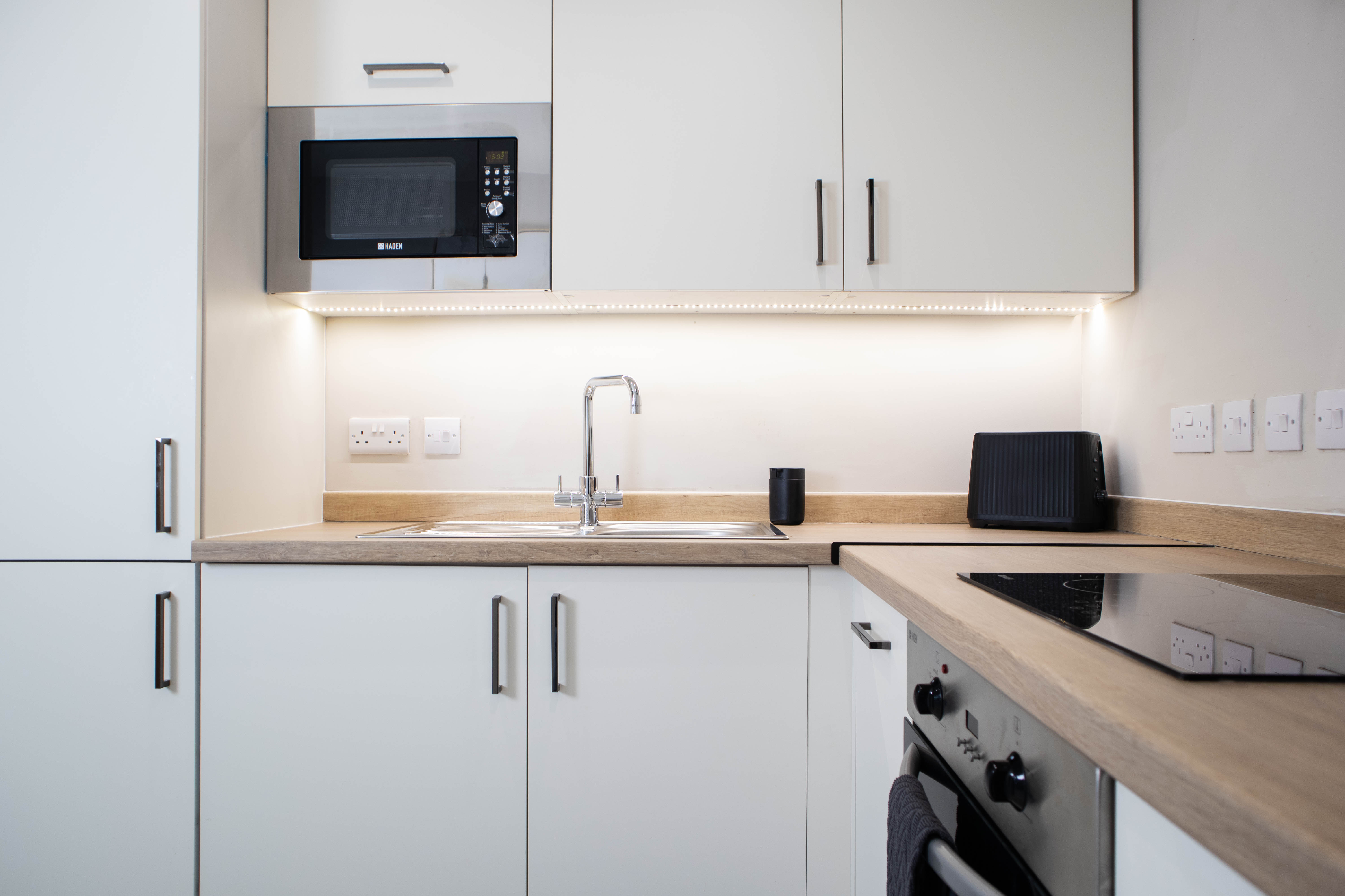 Bright modern kitchen with white cupbaords, electric stove and microwave