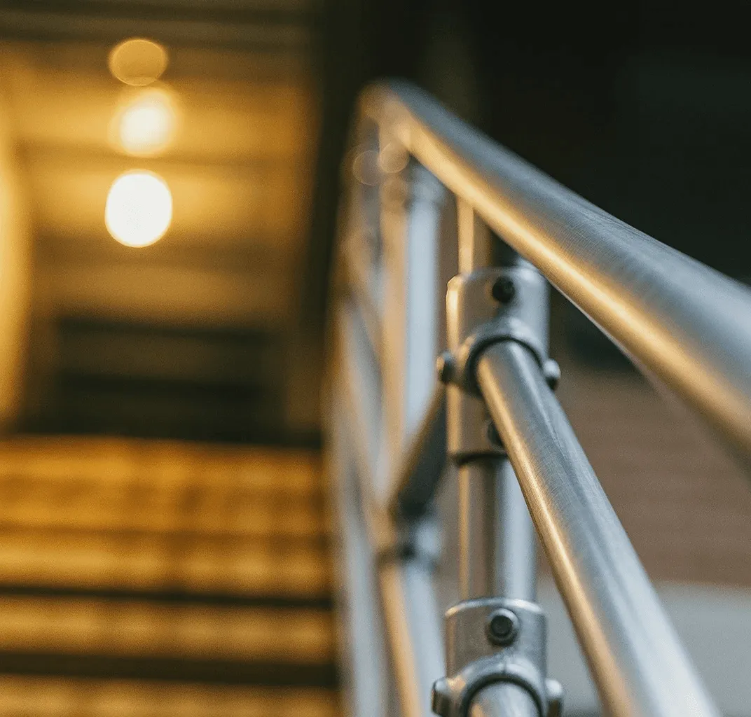 Image of a staircase with a metal railing, illuminated by warm light from a bulb above.