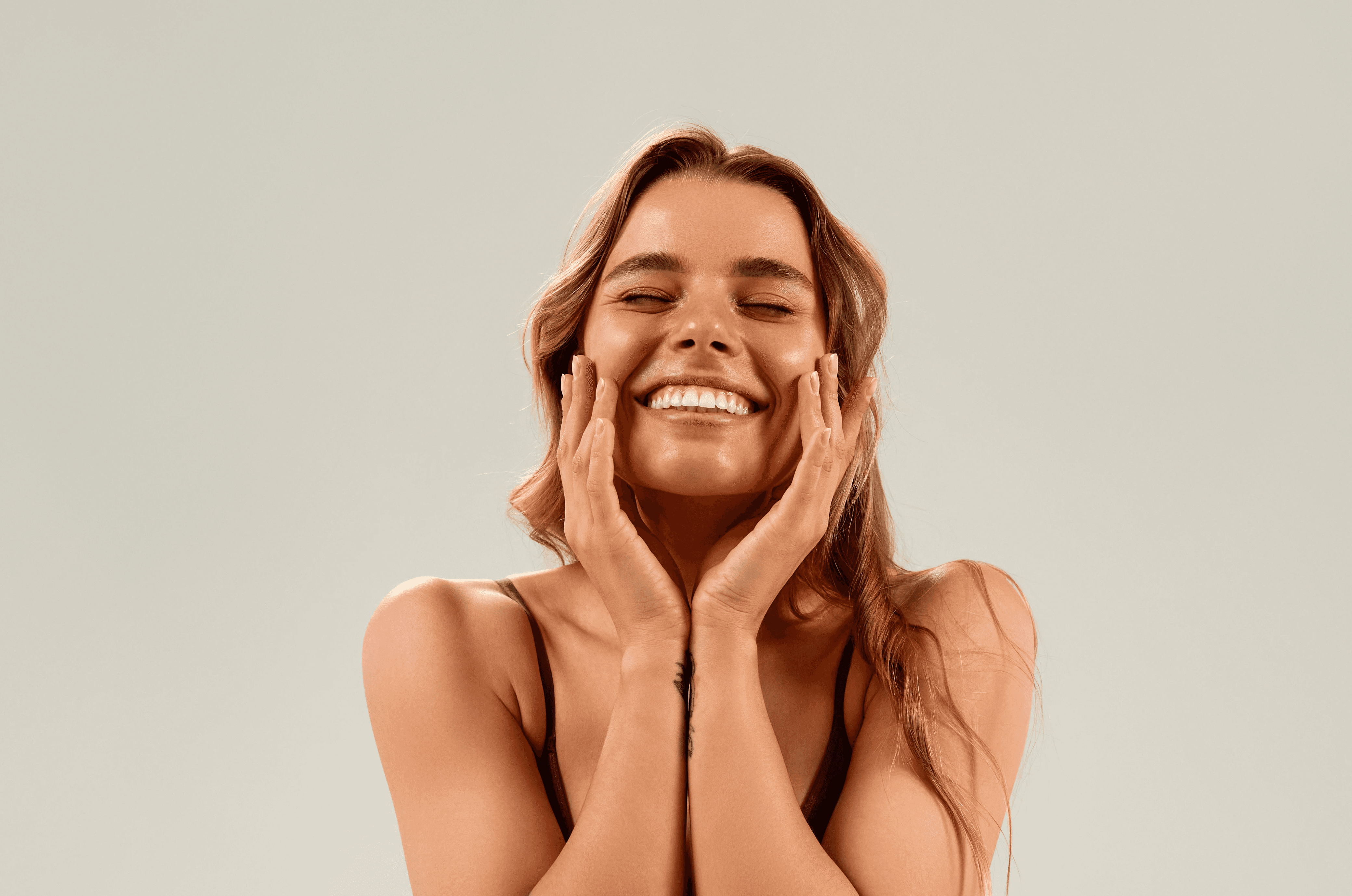 Close-up of a woman's hands adorned with rings and layered necklaces, highlighting her smooth skin and elegant jewelry