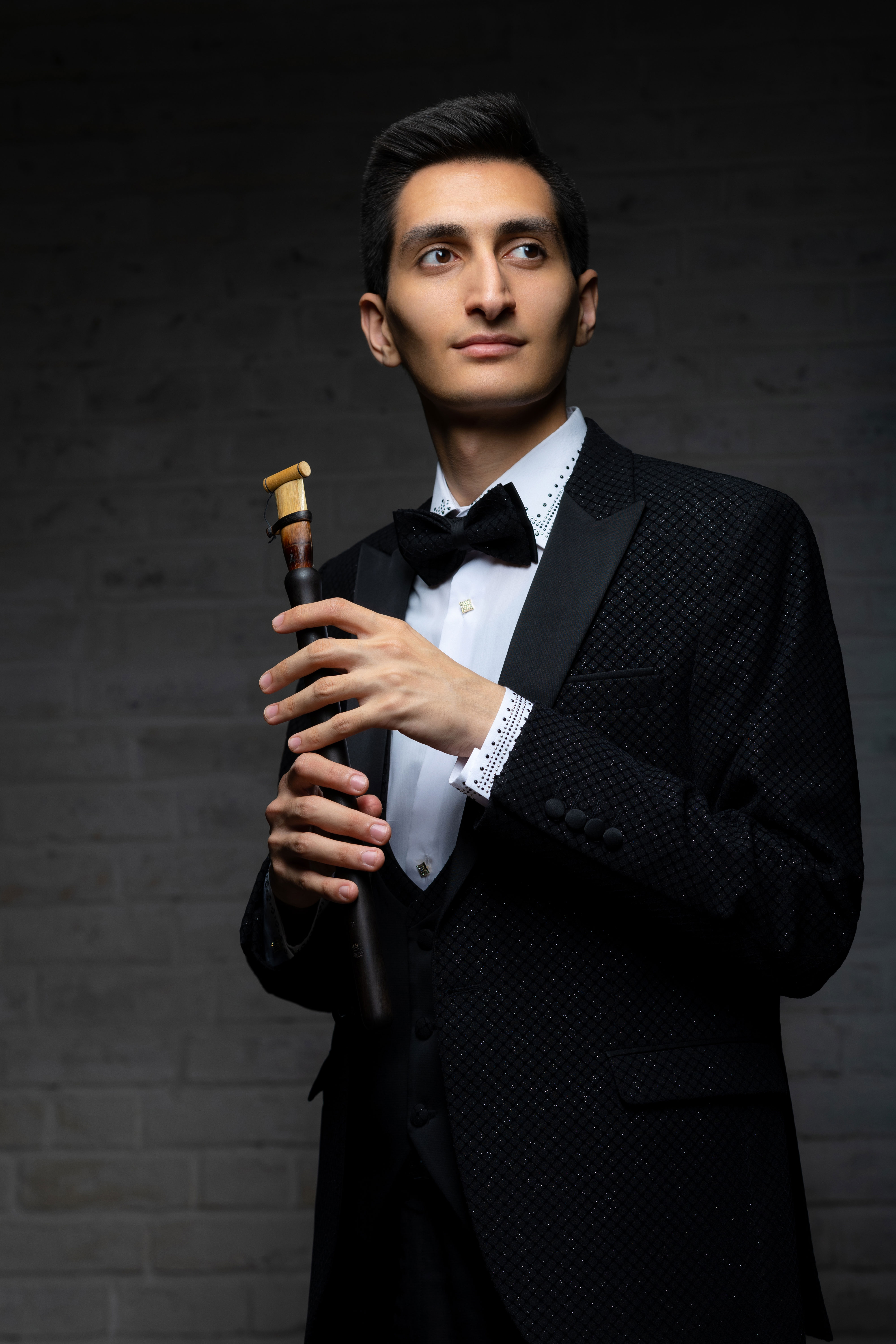 Erik Mirzoyan holding a duduk in formal concert attire