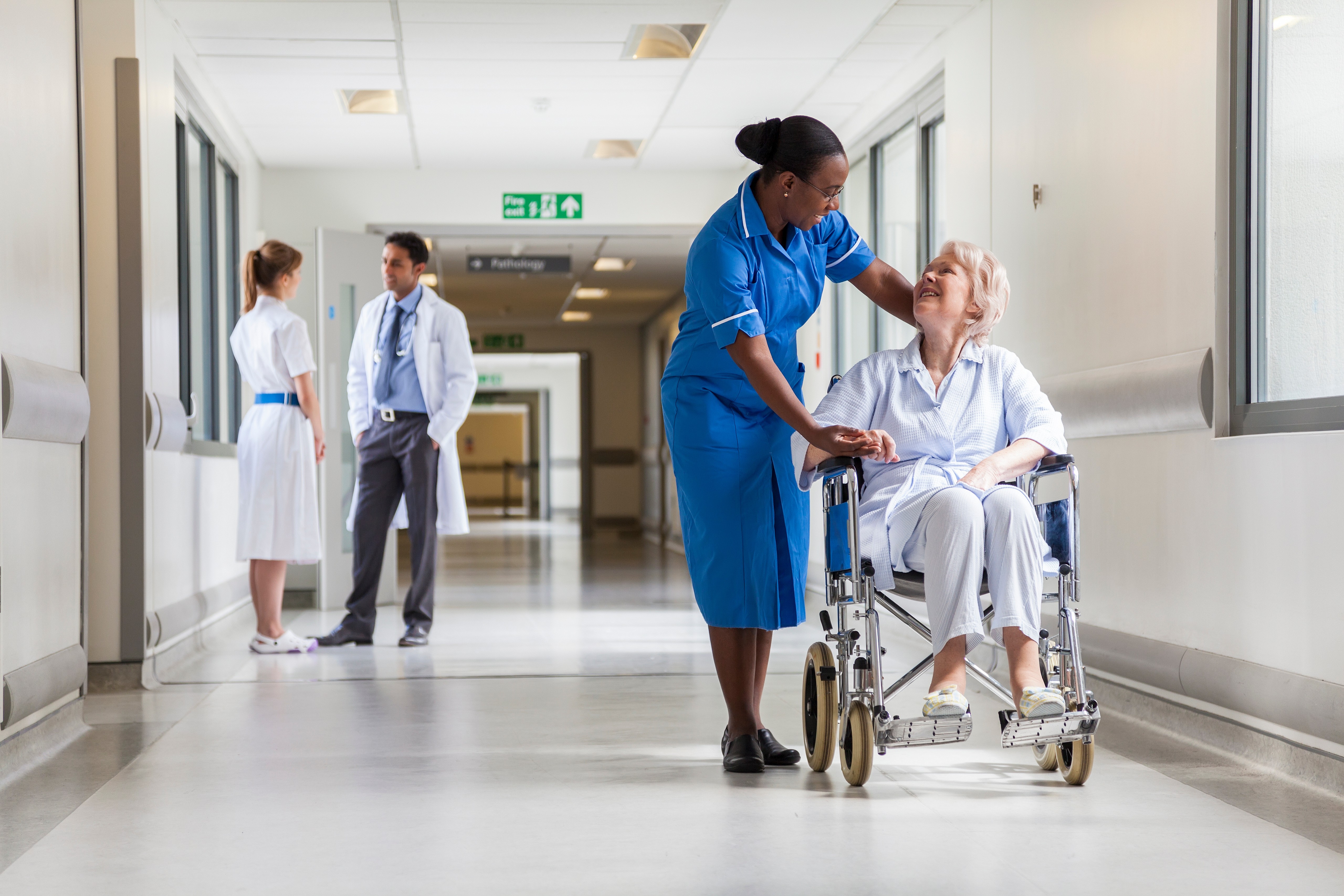 Nurse and patient in an NHS hospital corridor smiling