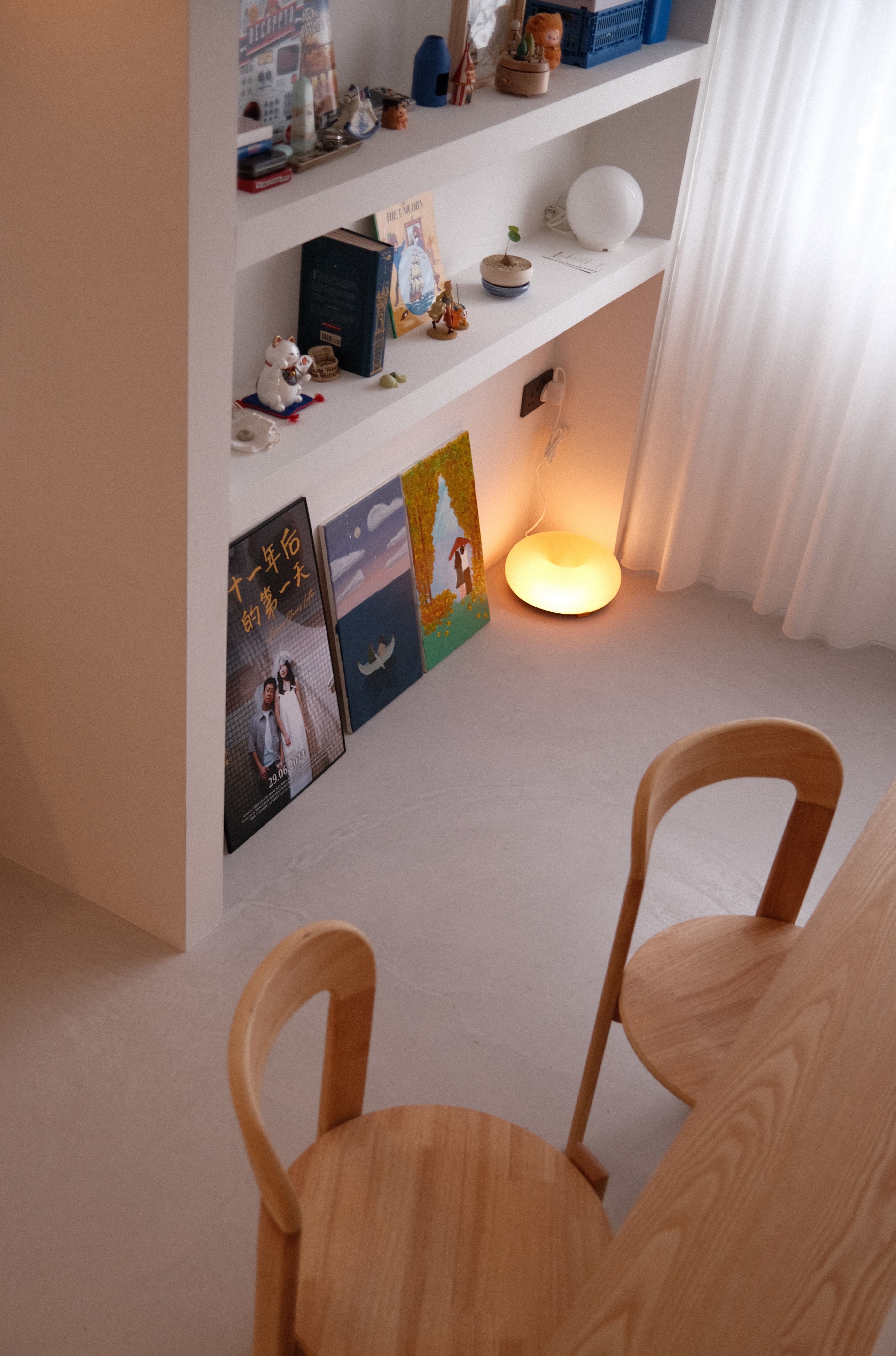 Built-in wall shelving in Tampines Wabi-O displaying curated decor, art prints, and ambient floor lamp, exemplifying modern wabi-sabi style.