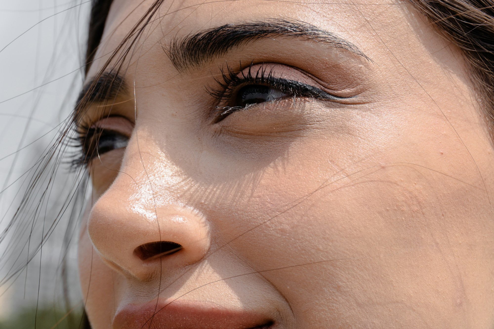 Close-up of a woman’s face in sunlight, showing smooth, bright skin under her eyes.