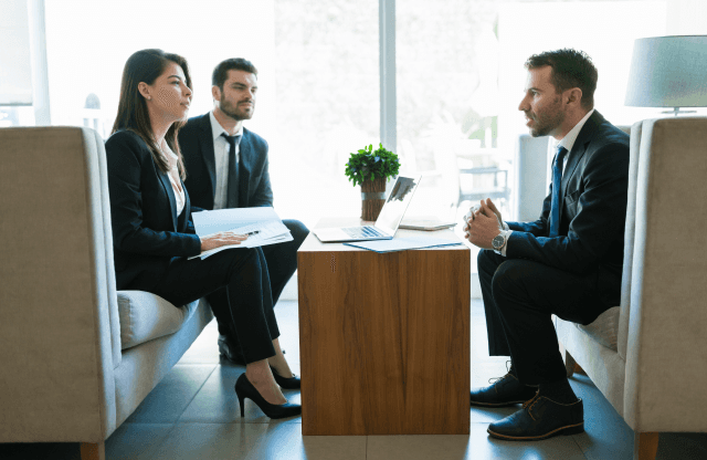 Two colleagues discussing data on a laptop screen.