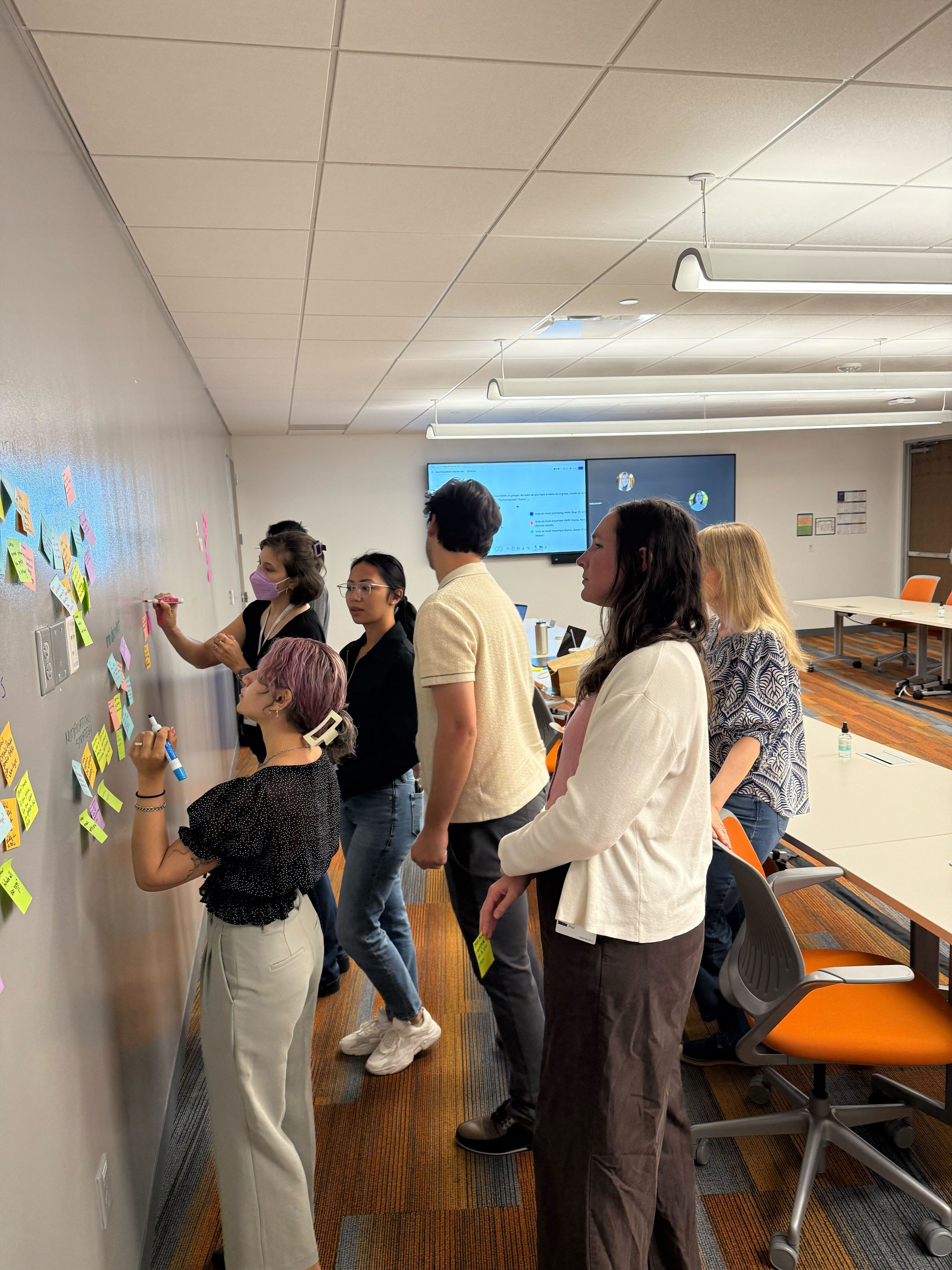 Group of people putting down sticky notes on wall