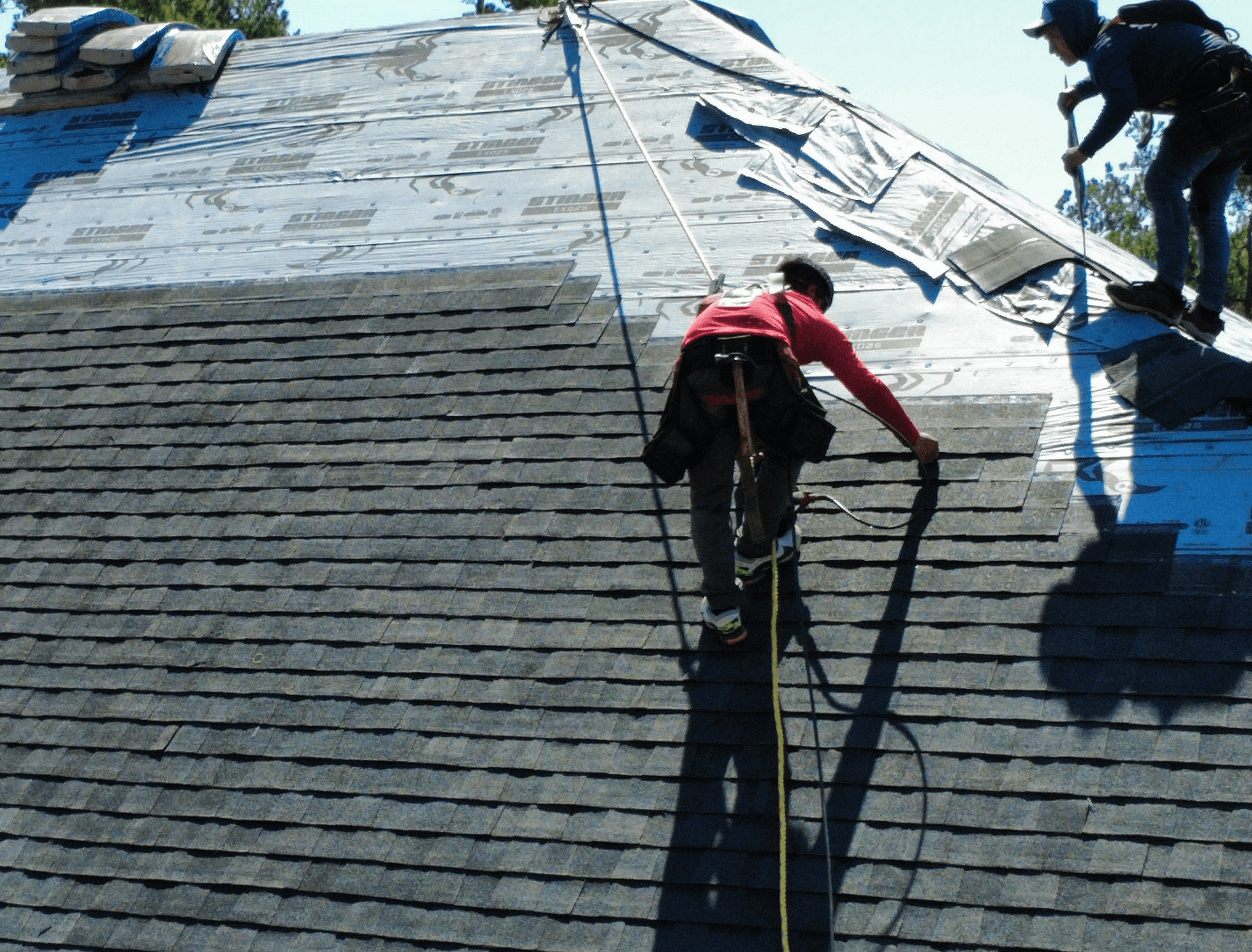 a man in a yellow shirt is working on a roof