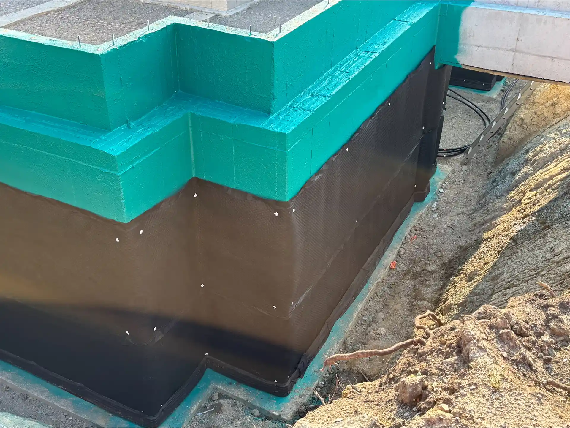 Photo of a concrete corner foundation with Rub-R-Wall waterproofing and Rub-R-Board drainage board installed