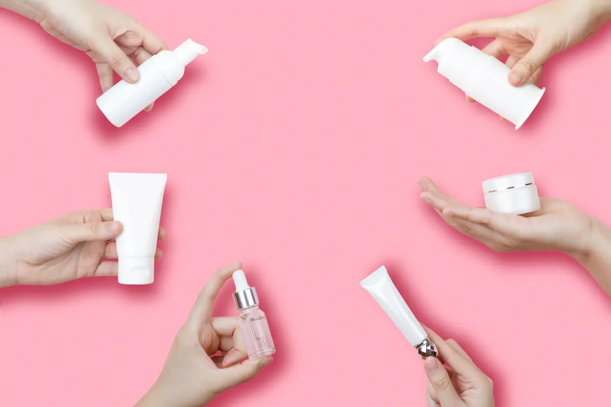 Hands holding skincare products.