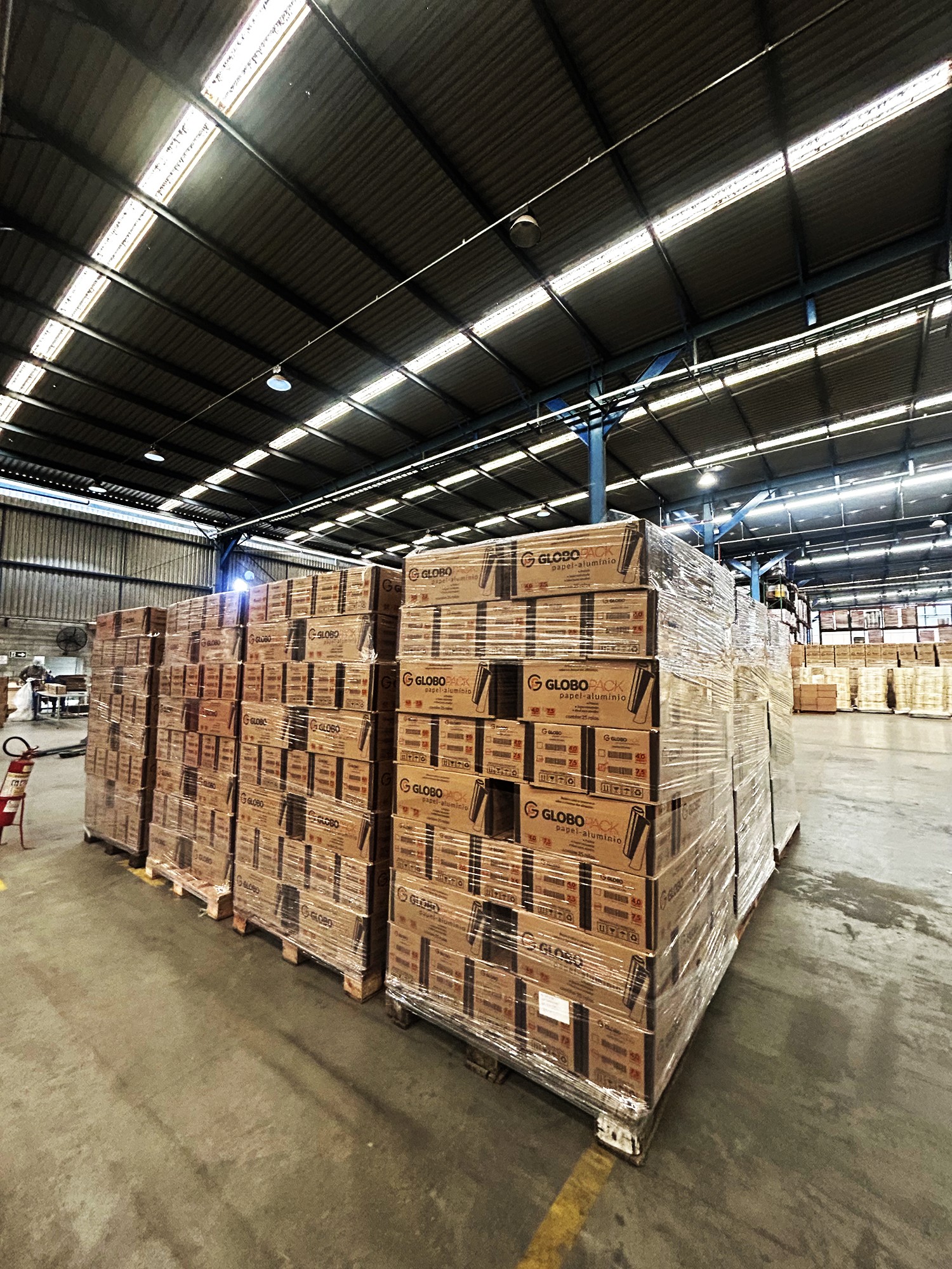 Estoque de papel-alumínio GLOBO PACK pronto para distribuição. Armazém organizado com caixas empilhadas de embalagens industriais para alimentos. Fornecimento e logística de papel-alumínio de alta resistência.