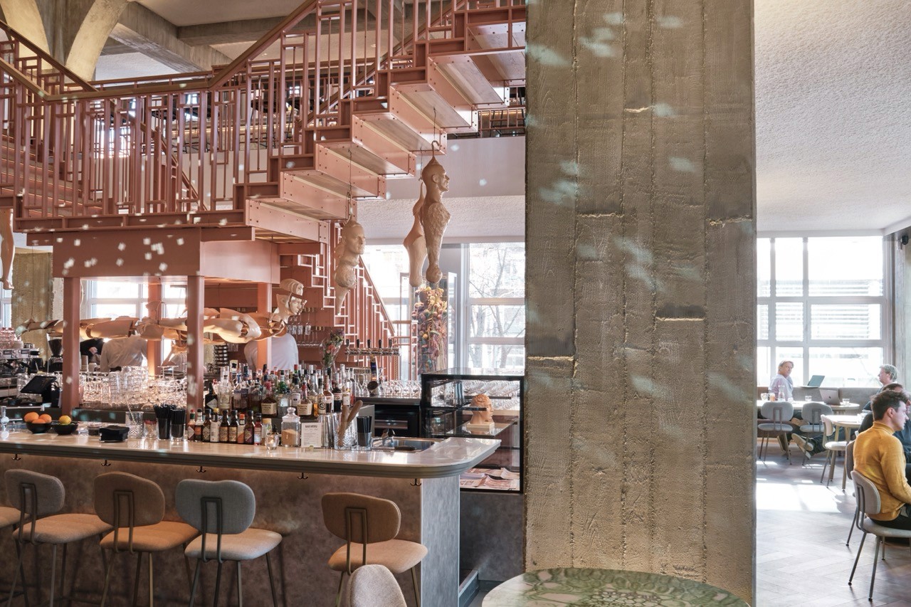 The interior of Capital Kitchen Amsterdam featuring the spiral staircase, wooden bar counter, and stylish decor.